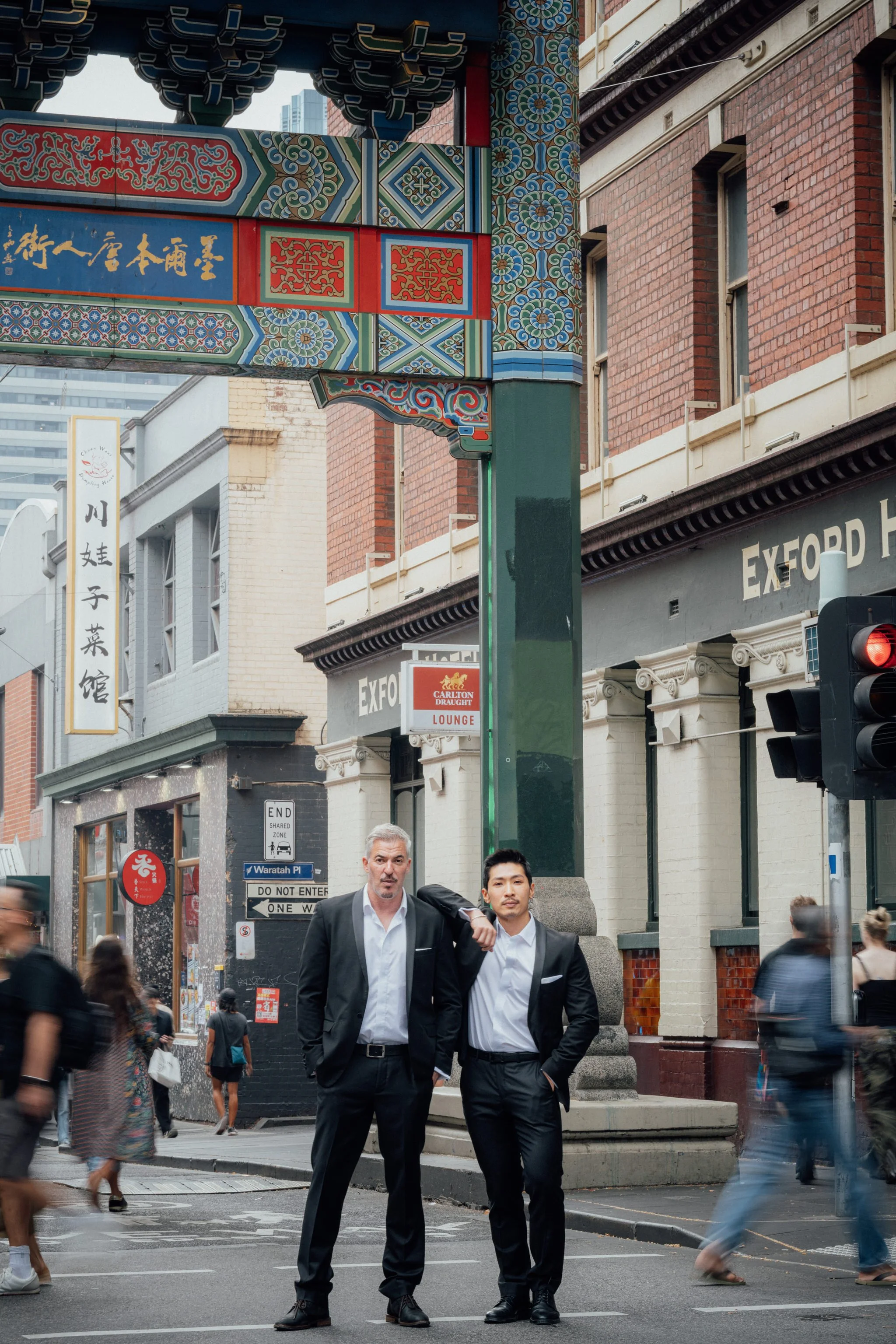 two grooms standing side by side on a street in chinatown