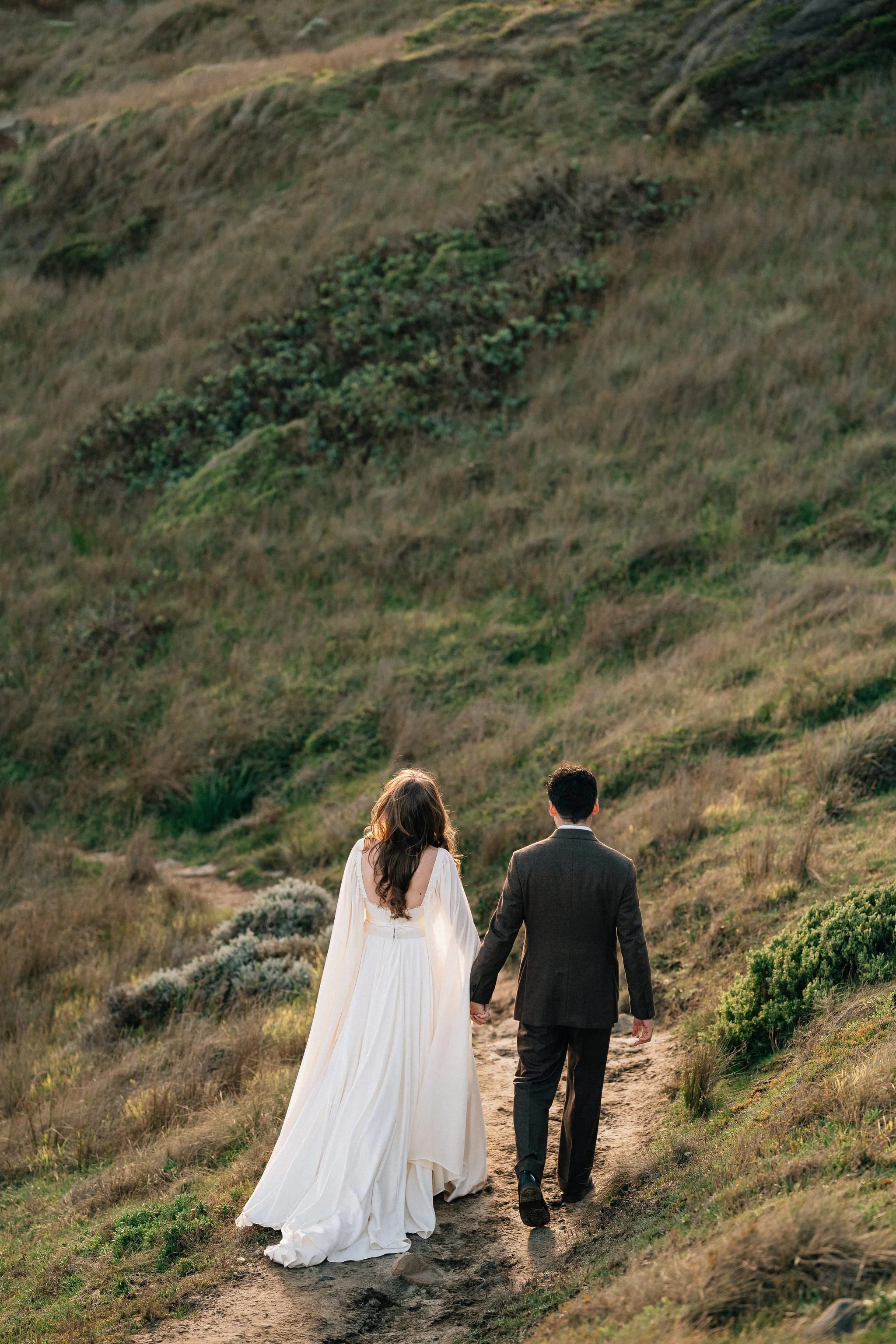 Groom and Bride holding hands walking in a valley