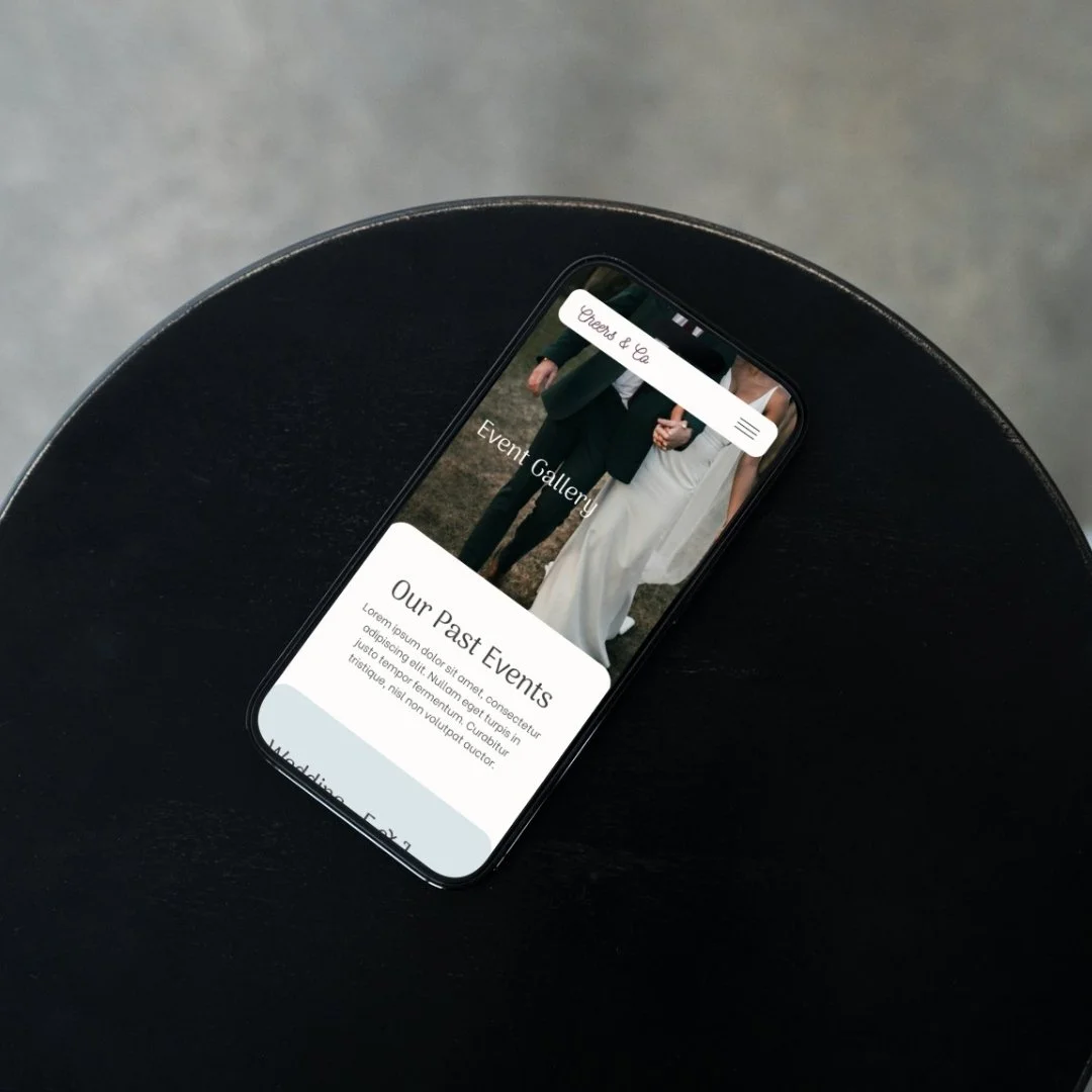 A smartphone resting on a black surface displays an event gallery webpage with an image of a couple in wedding attire, and text about past events.
