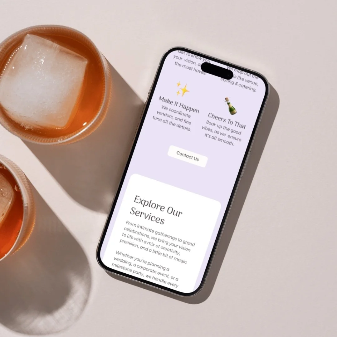 Smartphone displaying a website or app with sections about event services, next to two drinks with large ice cubes on a white surface.