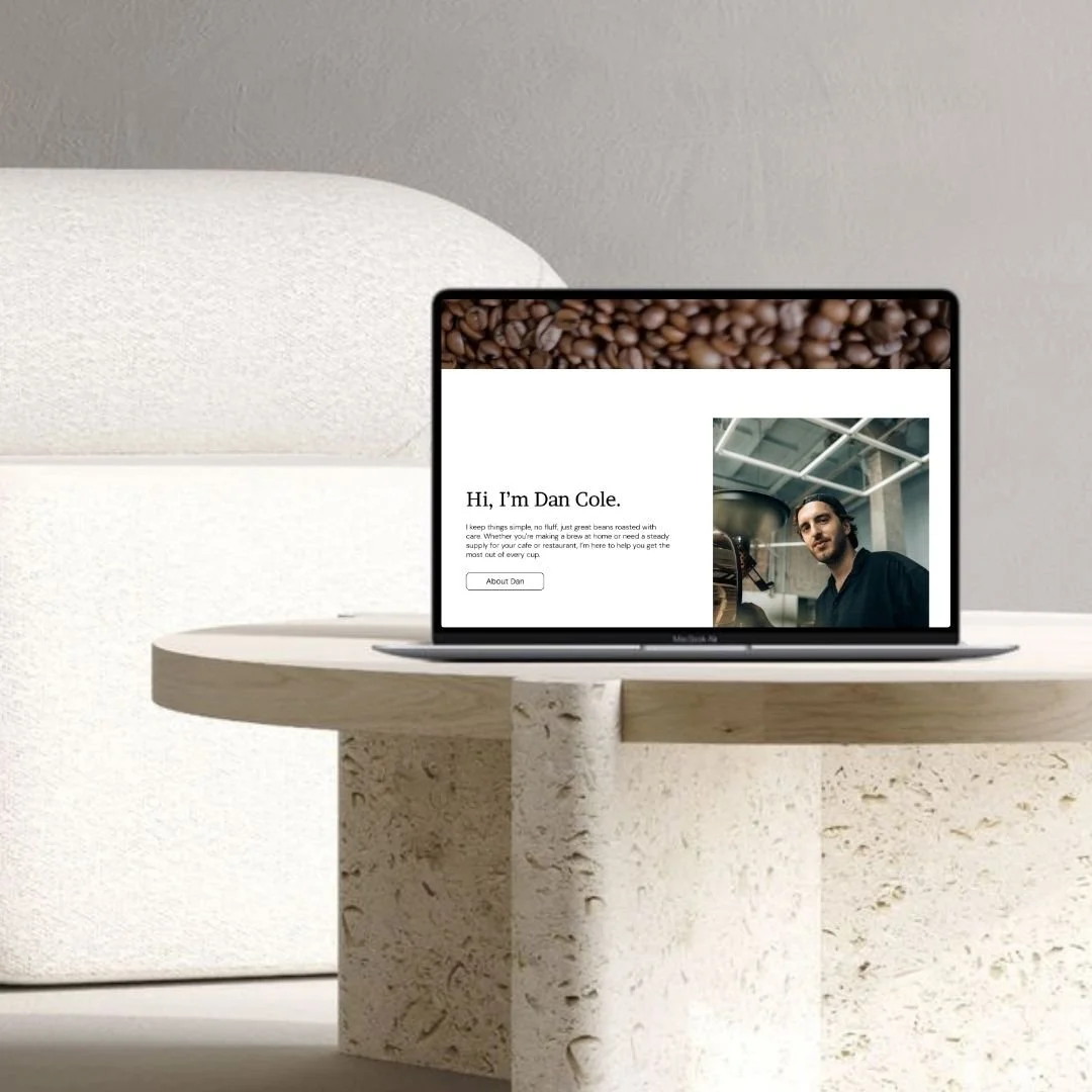 Laptop on a white textured table displaying a personal website with a photo of a man and text introducing Dan Cole.