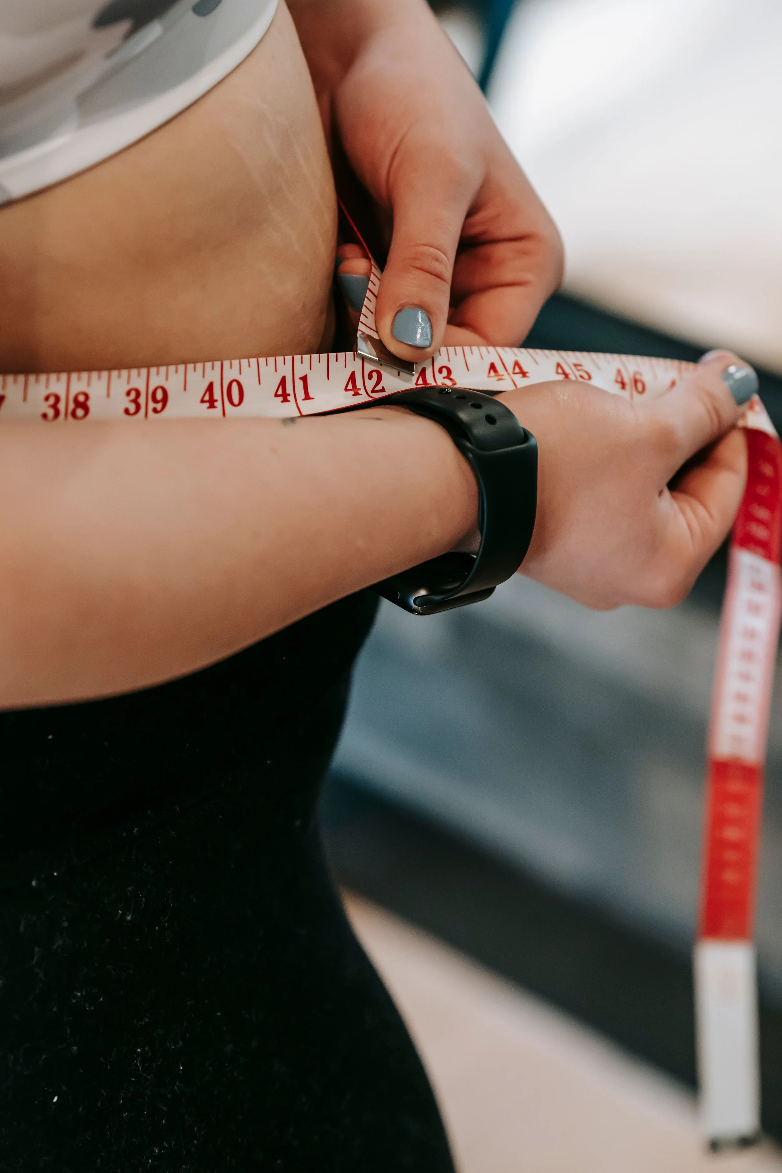 Woman measuring her waist with a tape measure