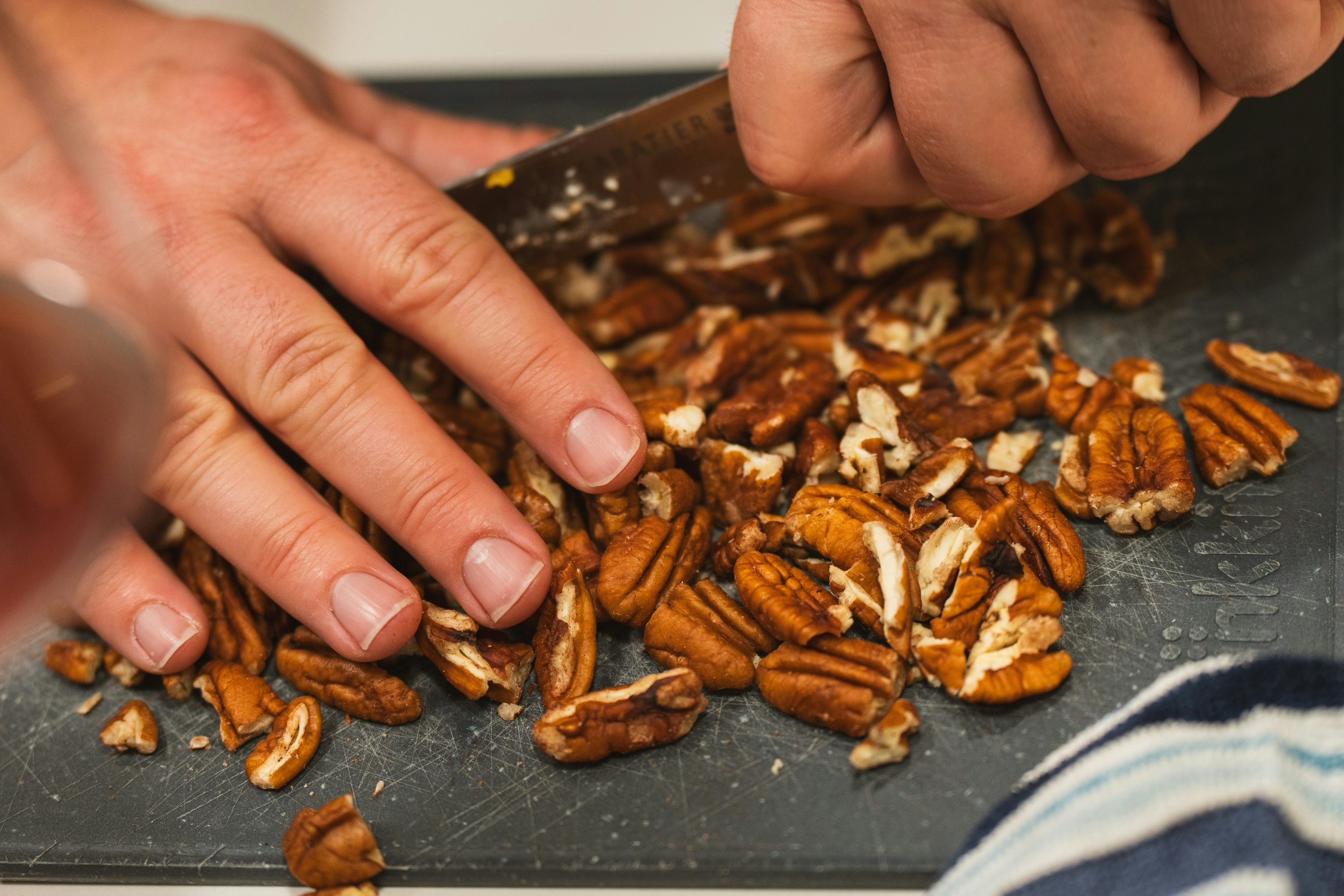 pecan nuts being chopped by hand on a chopping board