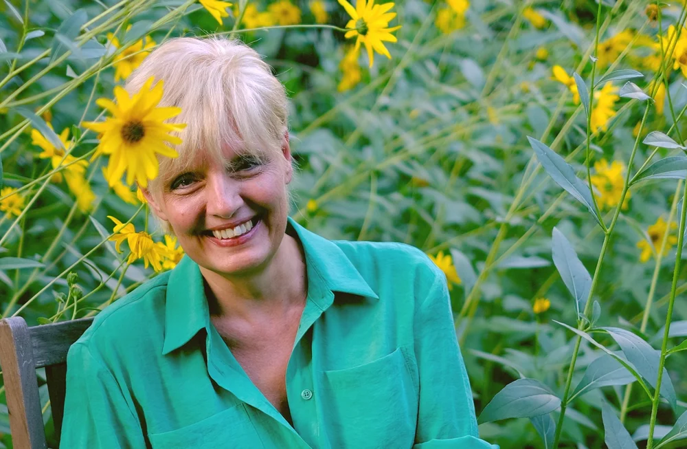 Joanna Szymanderska, uśmiechnięta, wśród żółtych kwiatów