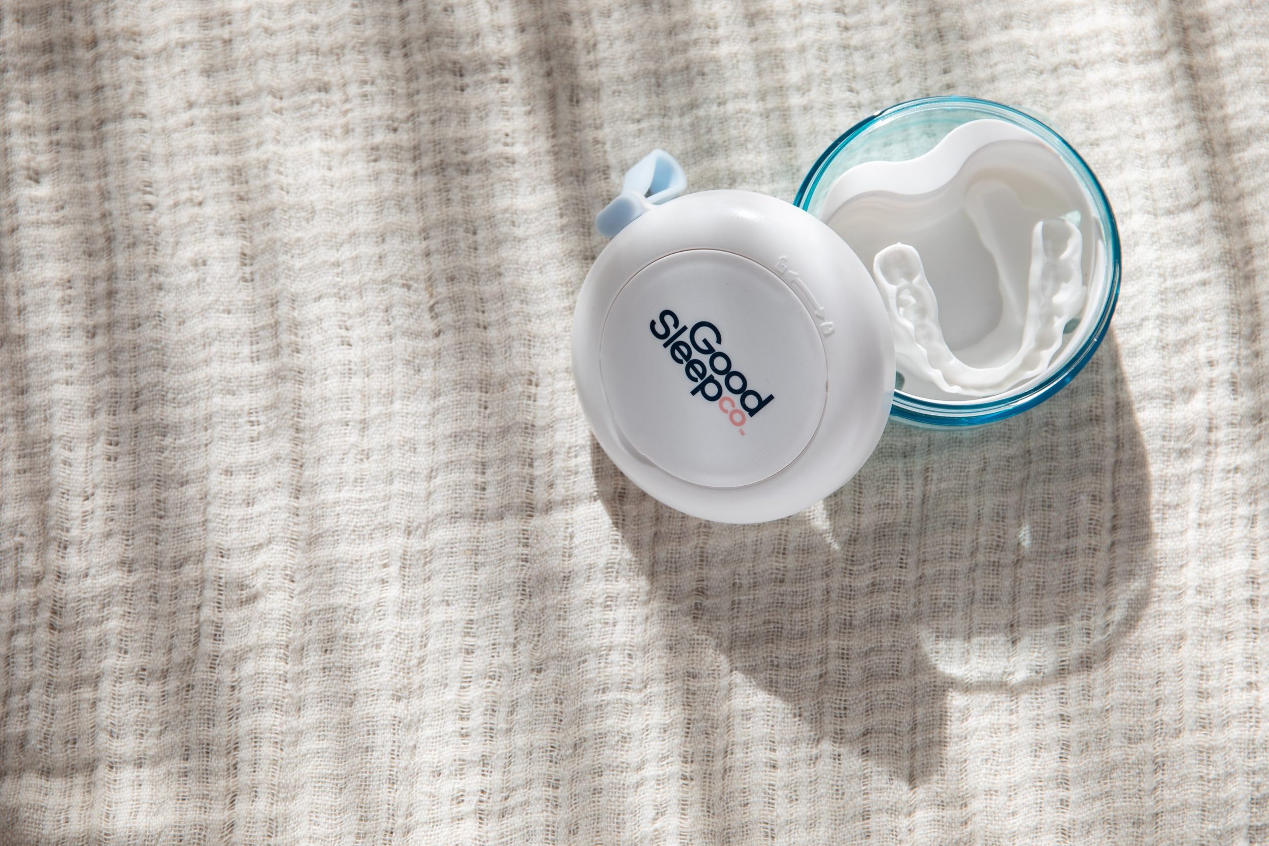 A clear blue container with a white dental impression inside, next to a white container with the words 'Good Sleep Co.' on its lid.