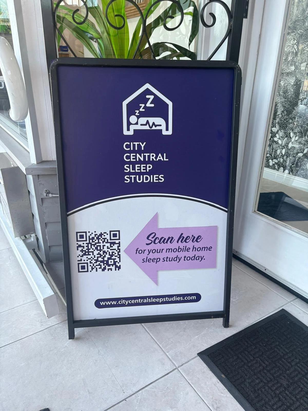 A standing signboard promoting City Central Sleep Studies with a purple background, displaying a sleeping person icon and text that says 'Scan here for your mobile home sleep study today.' A QR code is on the left side, and the website URL www.citycentralsleepstudies.com is at the bottom.