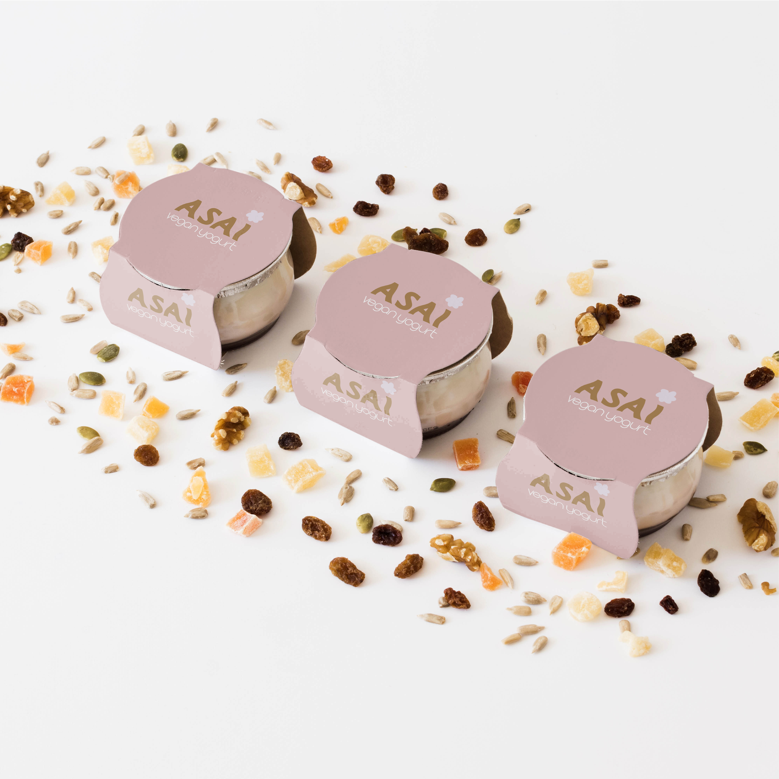 Trois pots de yaourt végétalien ASAI, entourés de fruits secs et graines sur fond blanc.