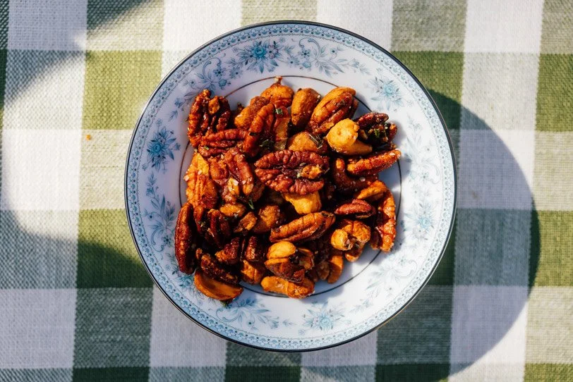 a bowl of roasted nuts on a light-colored fabric surface.