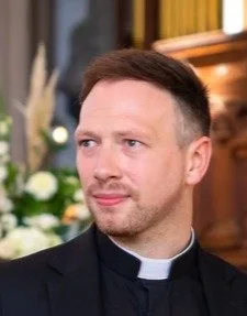 A man dressed as a priest with a short beard.