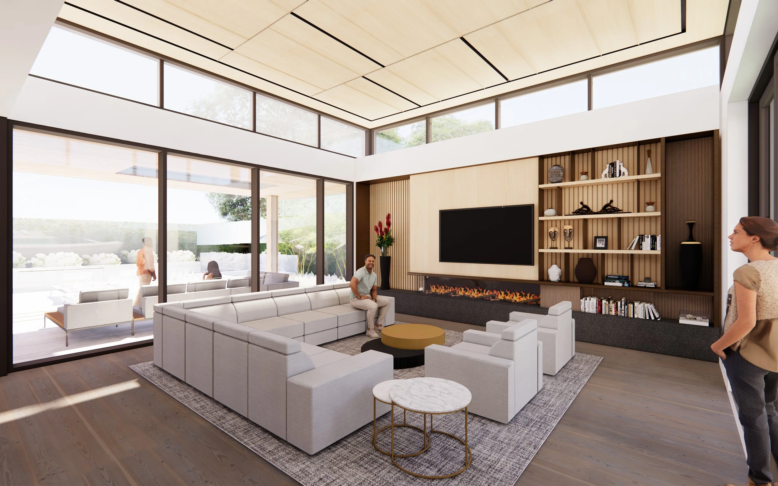 Modern living room with a large white sectional sofa, coffee tables, a flat-screen TV, and built-in shelving. Floor-to-ceiling windows and glass doors let in natural light, with a view of outdoor seating and greenery.