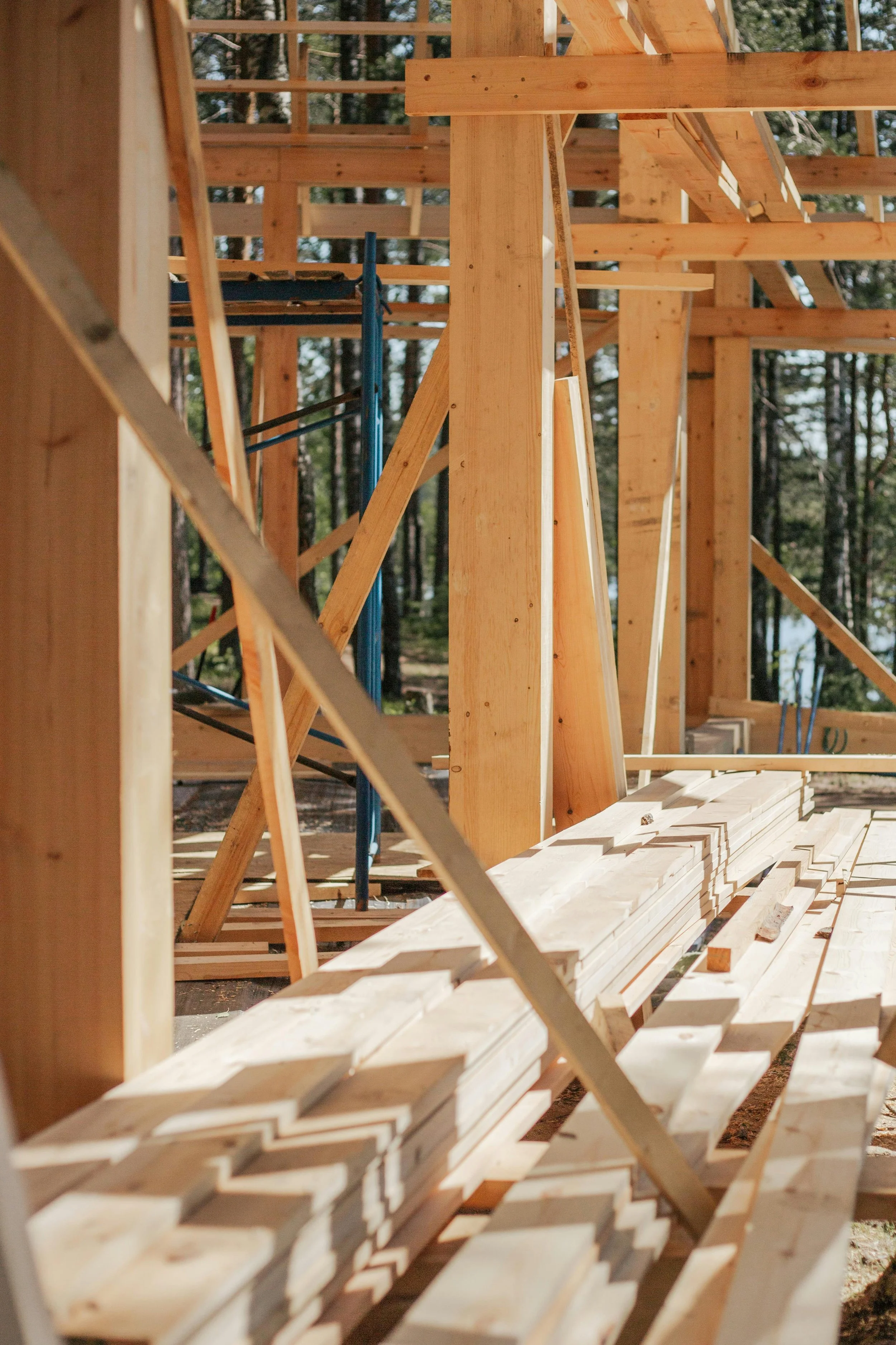 Construction site of a wooden building framed with lumber in a forested area.