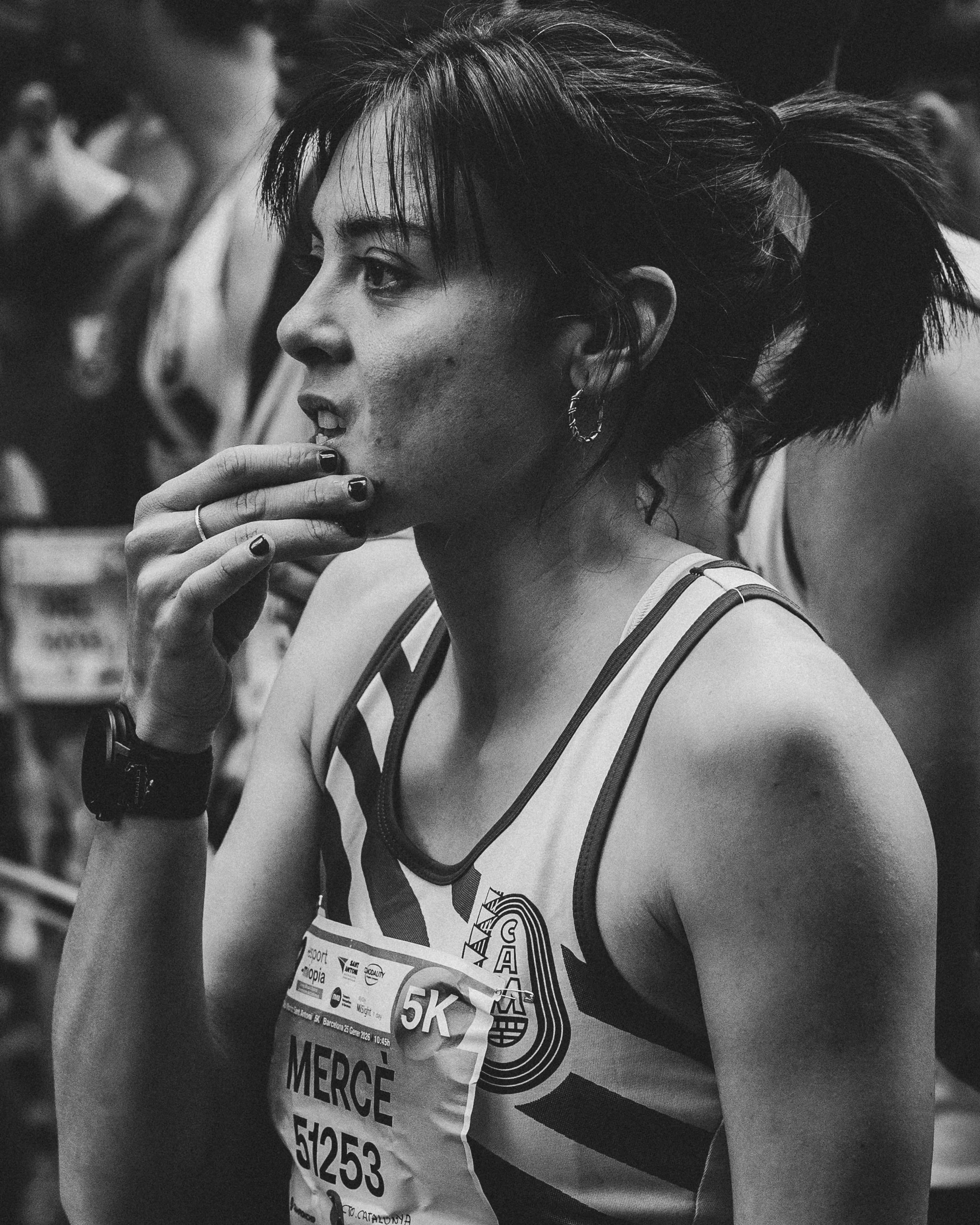 Mujer en una carrera, vista lateral, con expresión concentrada y en ropa deportiva, en un entorno de competencia.