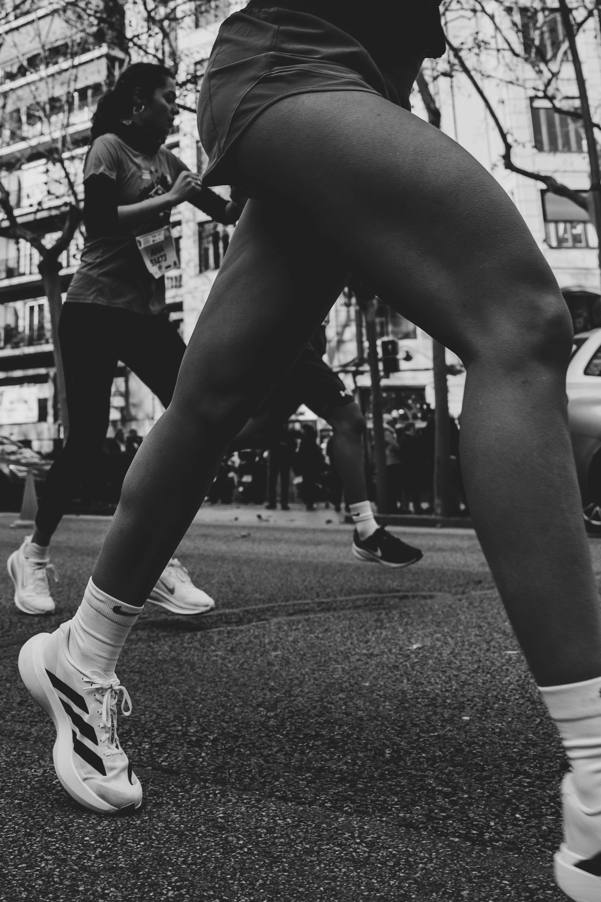 Atletas corriendo en una carrera en la ciudad, vista en ángulo desde abajo.
