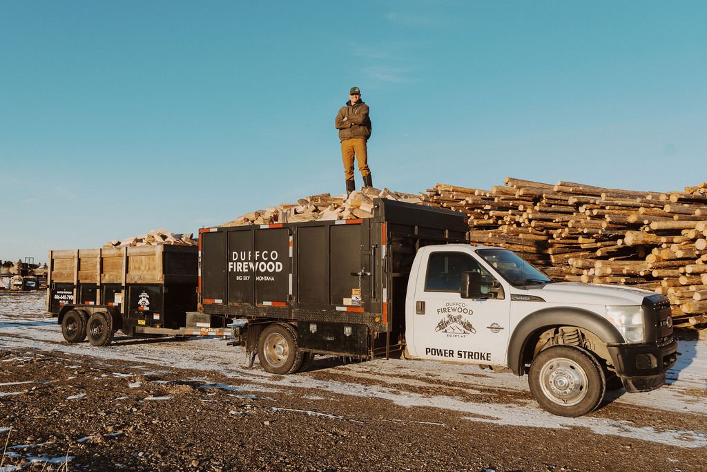 Duffco Firewood founder, Matt Duffy, standing on top of firewood stacked in a Duffco branded delivery truck.