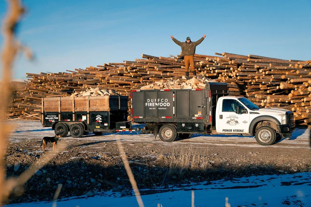 Duffco Firewood founder, Matt Duffy, standing on top of firewood stacked in a Duffco Firewood branded truck. 