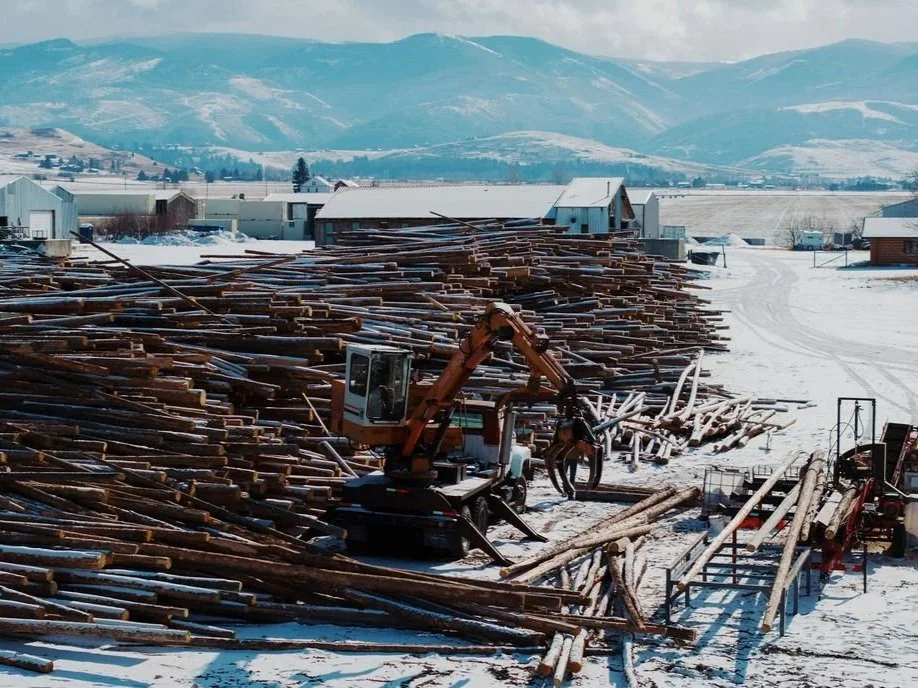 A photo of the woodyard with a truck-mounted log loader in action.