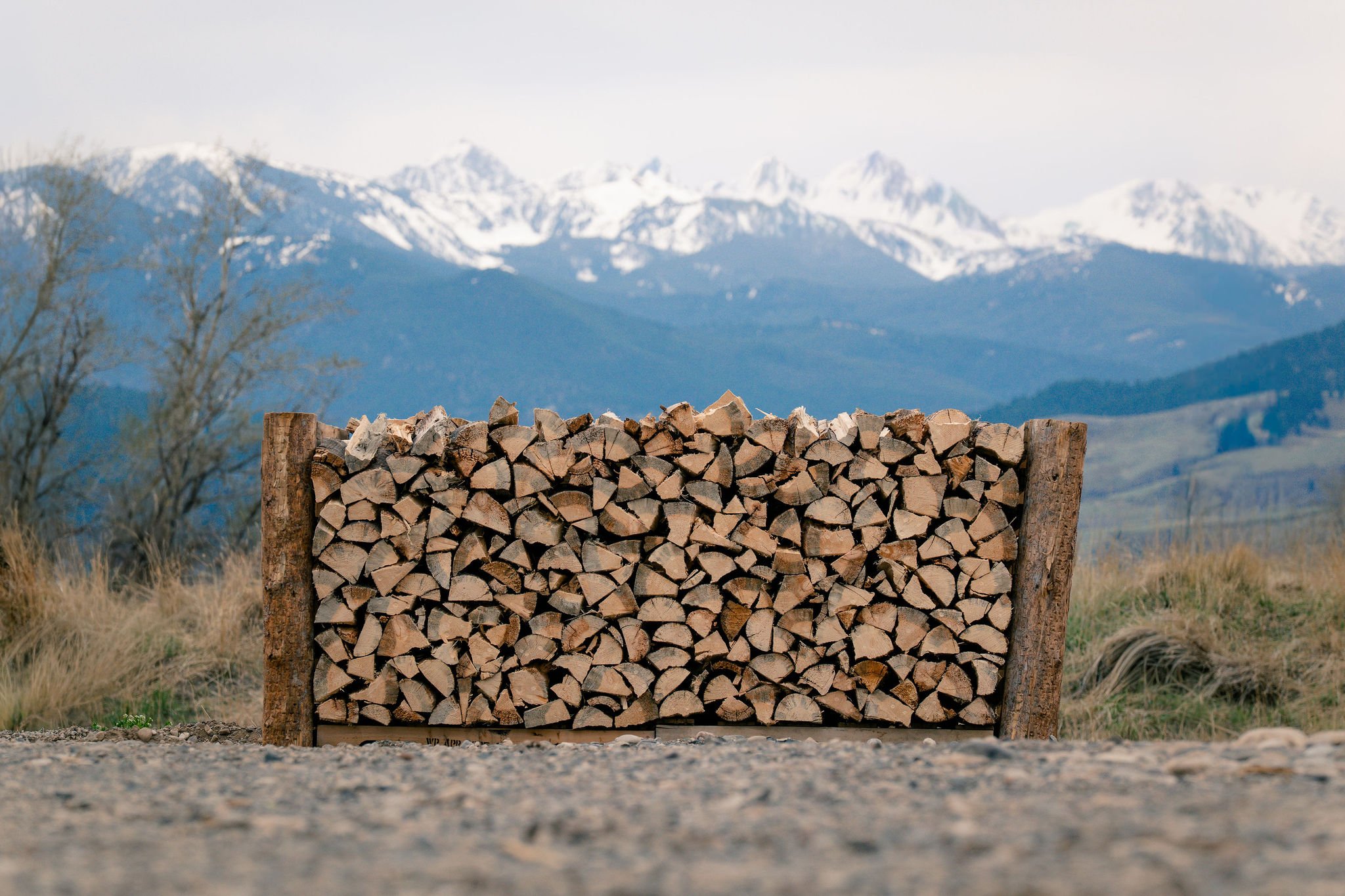 A full cord of firewood with mountains behind it.