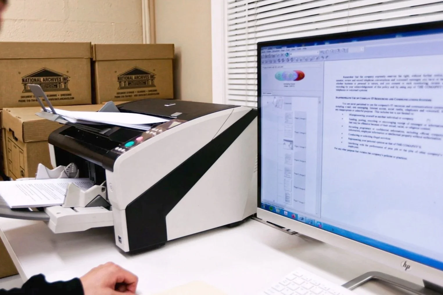 An employee at National Archives Inc. scanning paper documents for digital conversion and records management.