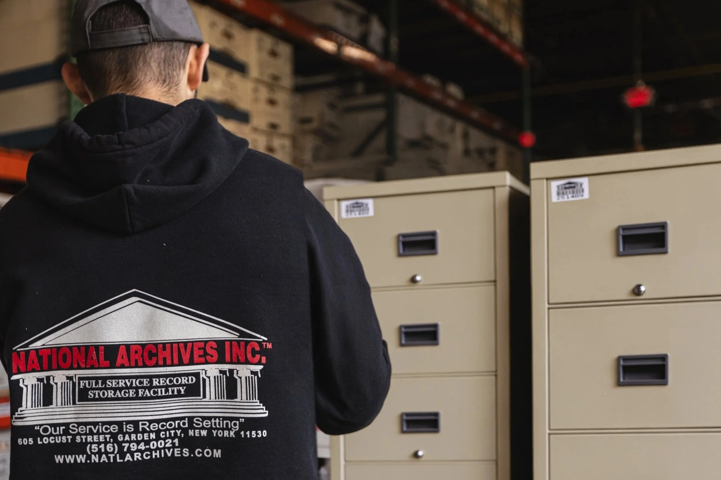 An employee of National Archives Inc. standing in front of secure vault filing cabinets used to store important documents and records.