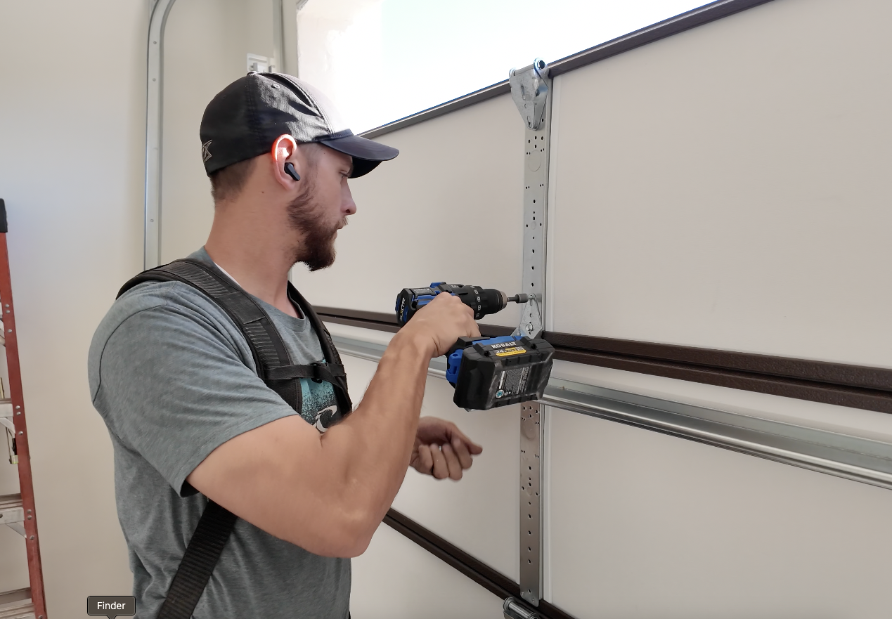 Advanced Garage Door Works technician installing garage door track with a cordless drill