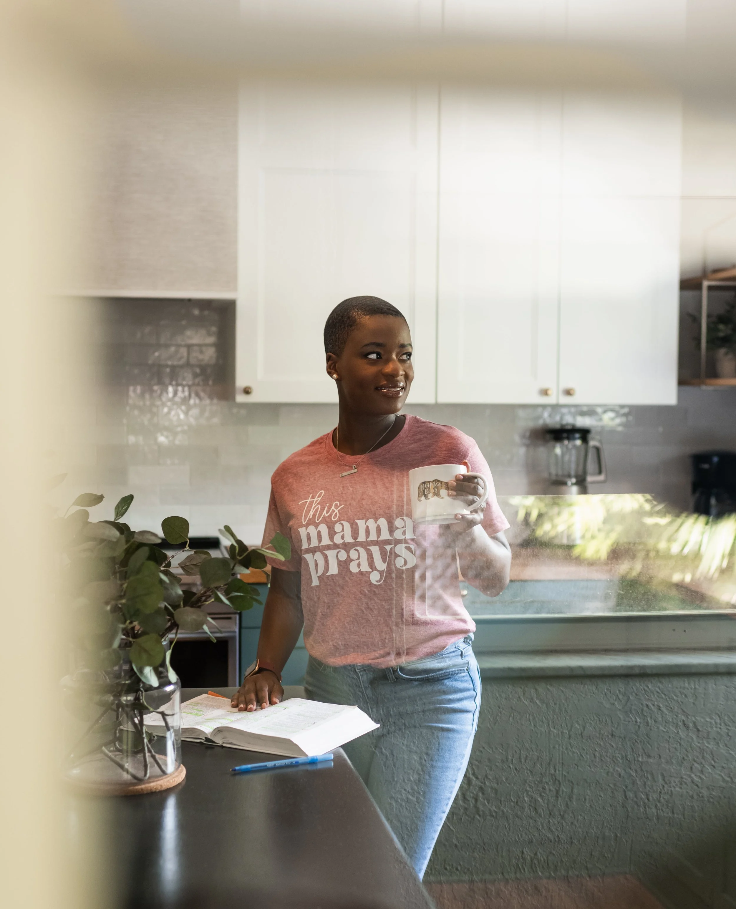 Christian Doula Dee Larkin holding mug and bible in kitchen at a Central Florida home.
