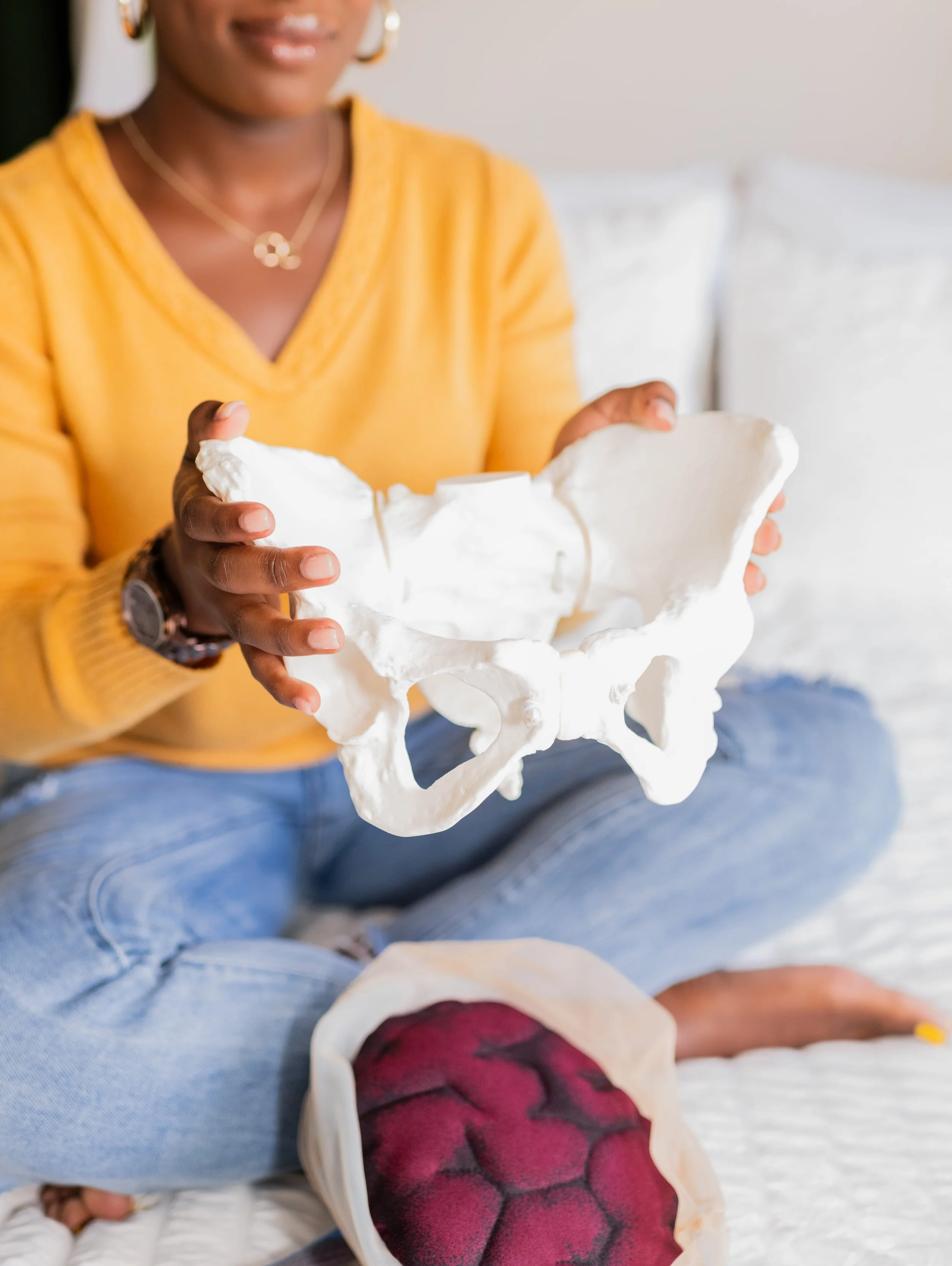 Holistic Doula Dee Larkin holding pelvis model on bed in South Tampa, Florida.
