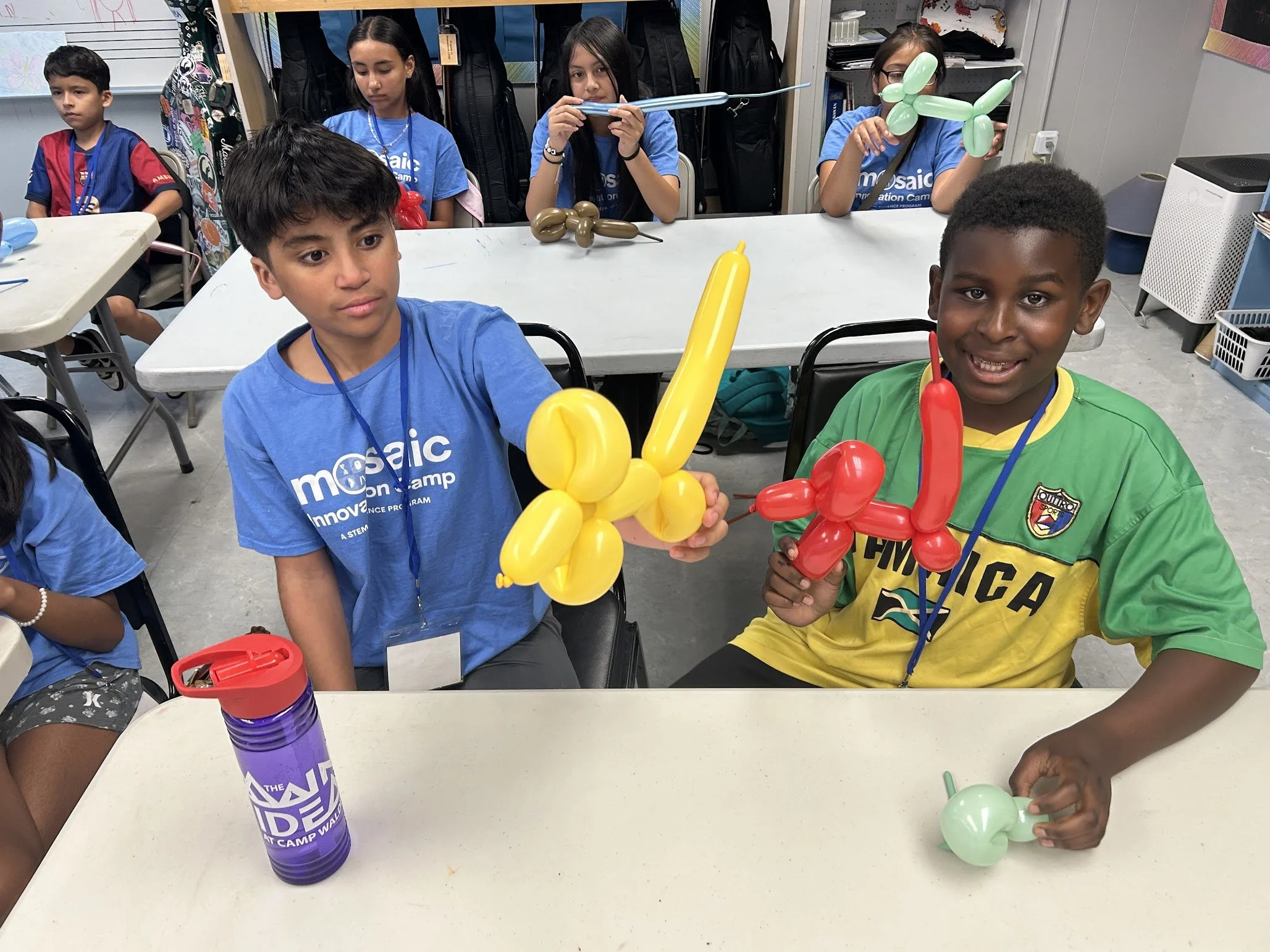 Two boys with a twisted balloon animal of a yellow and red dog that they created