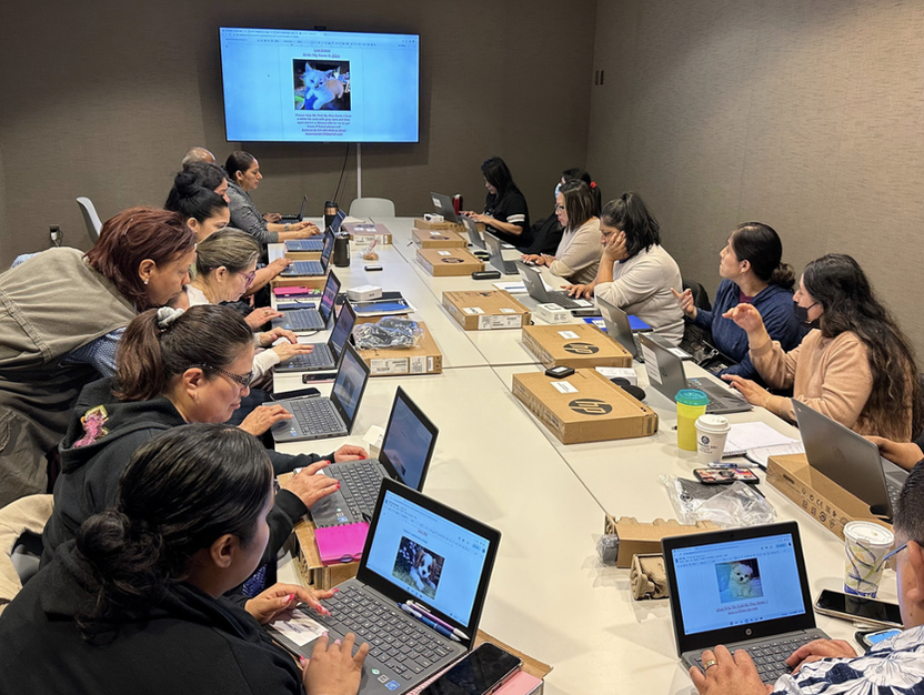 Adults with laptops around a big table