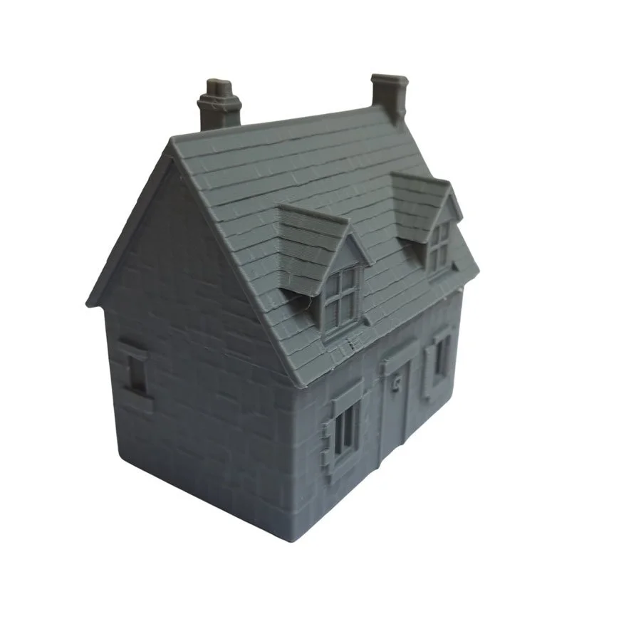 Gray plastic model of a house with a pitched roof, dormer window, and chimney.