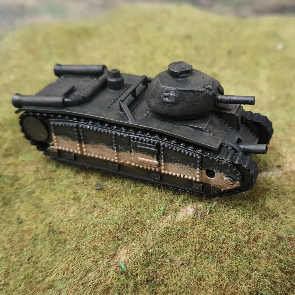 A small, detailed model of a black military tank on a grassy surface.