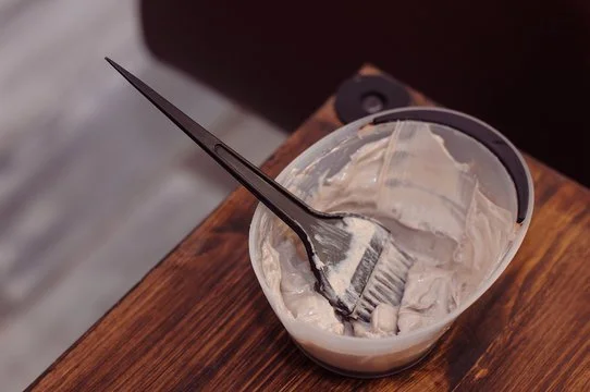 A plastic container with leftover ice cream and a fork resting inside, placed on a wooden surface.