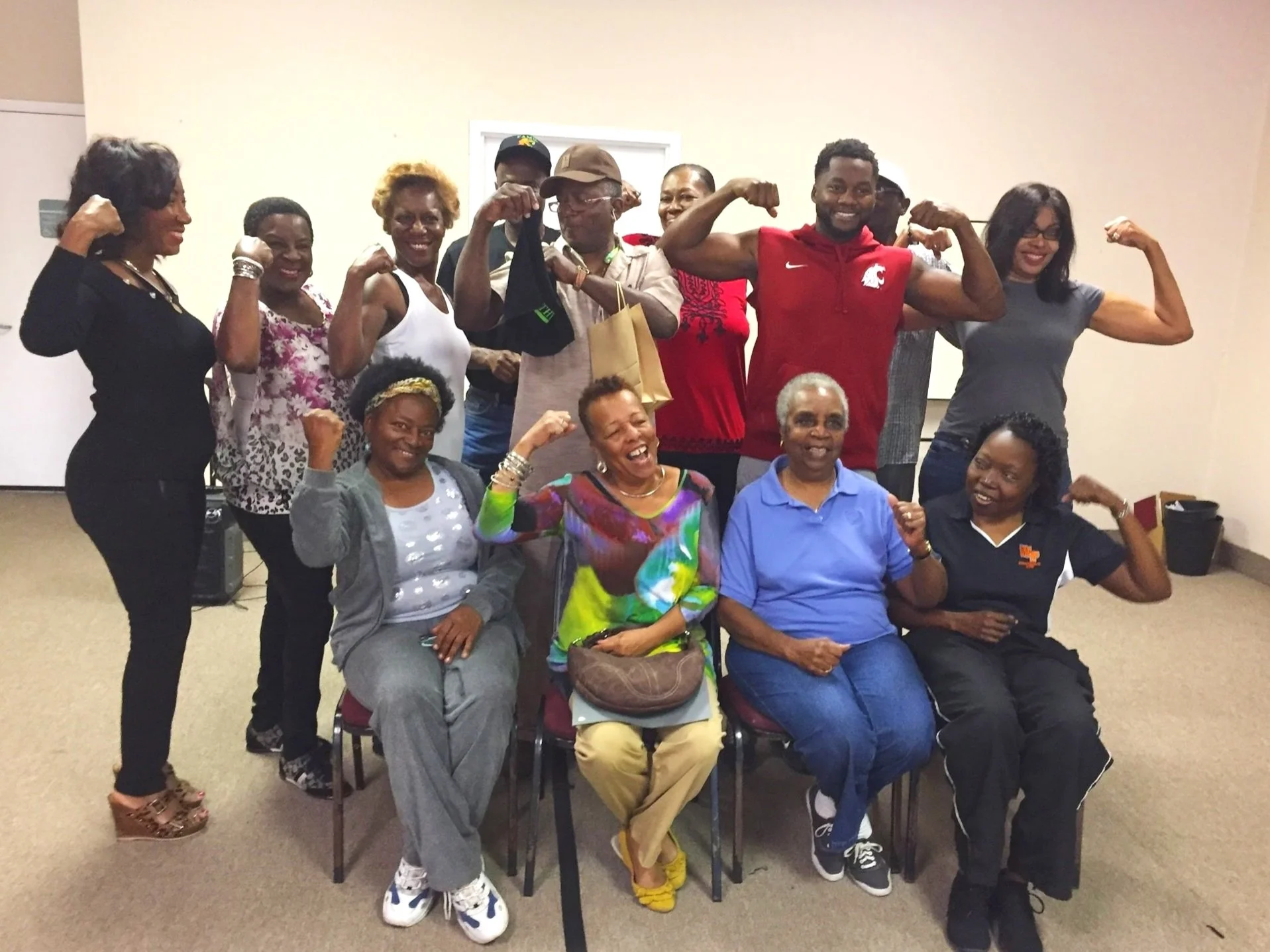 Group of diverse women posing with flexed biceps, smiling, in an indoor setting.