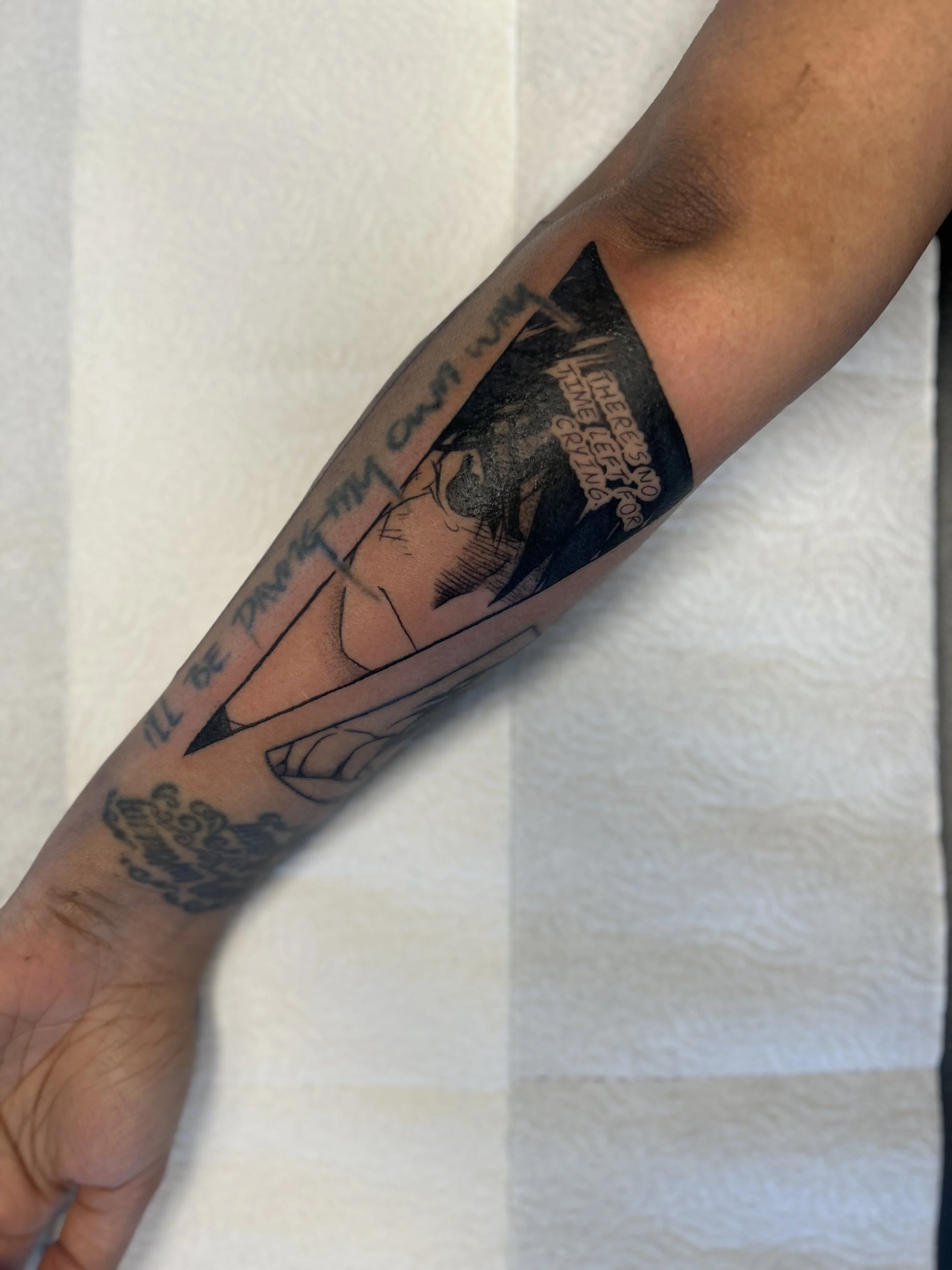 Blackwork anime-inspired gap‑filler tattoo with fine line technique and lettering