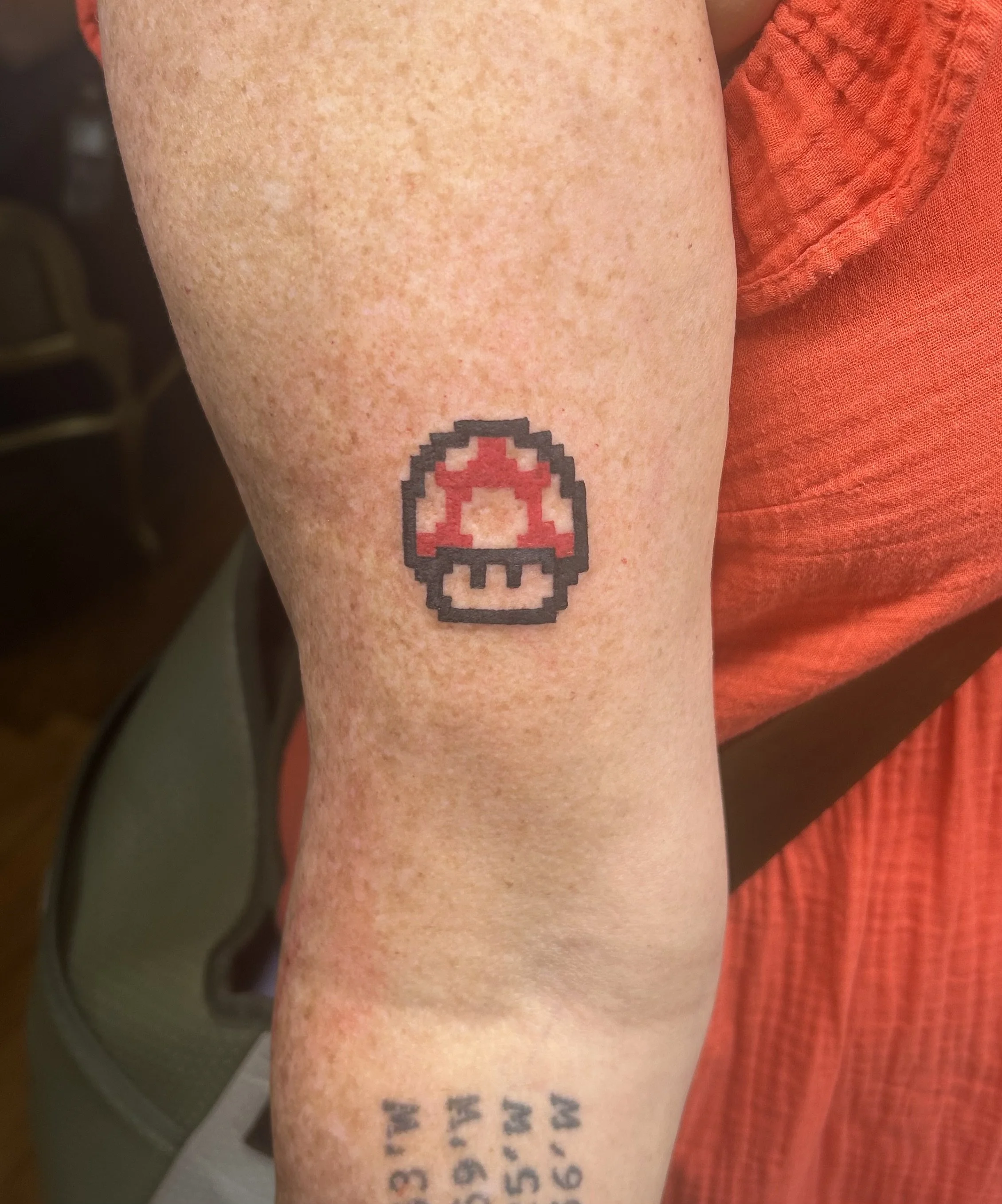 Full‑color pixel art red Toad mushroom tattoo (Super Mario Bros.), retro gaming style