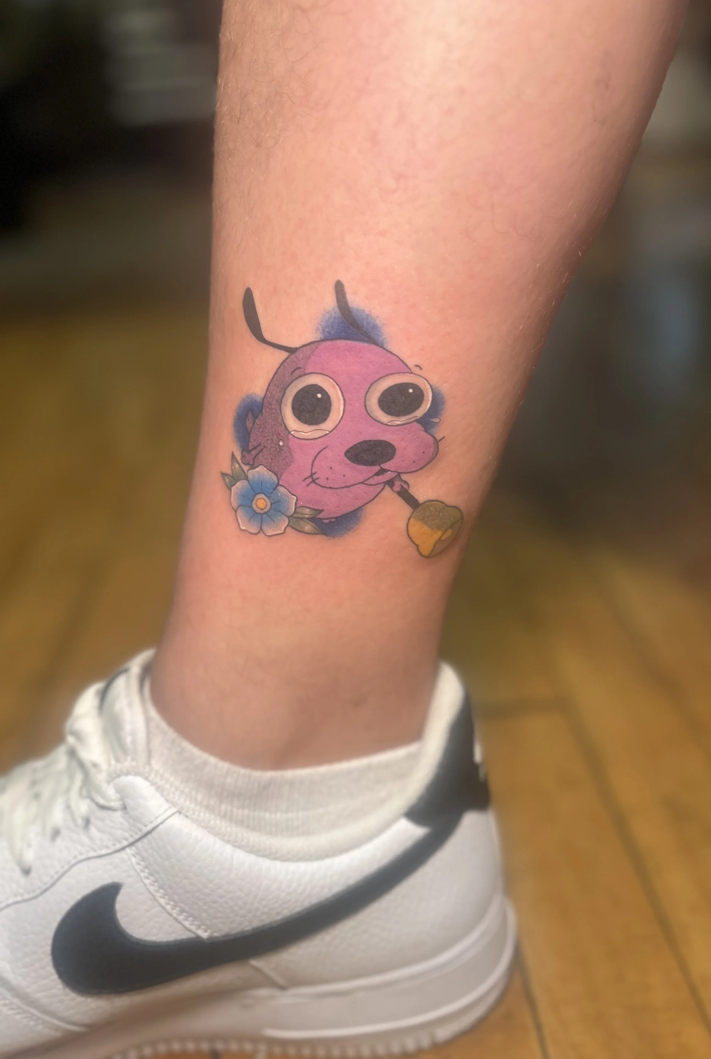 Full‑color Courage the Cowardly Dog tattoo with traditional flower accent, cute custom style