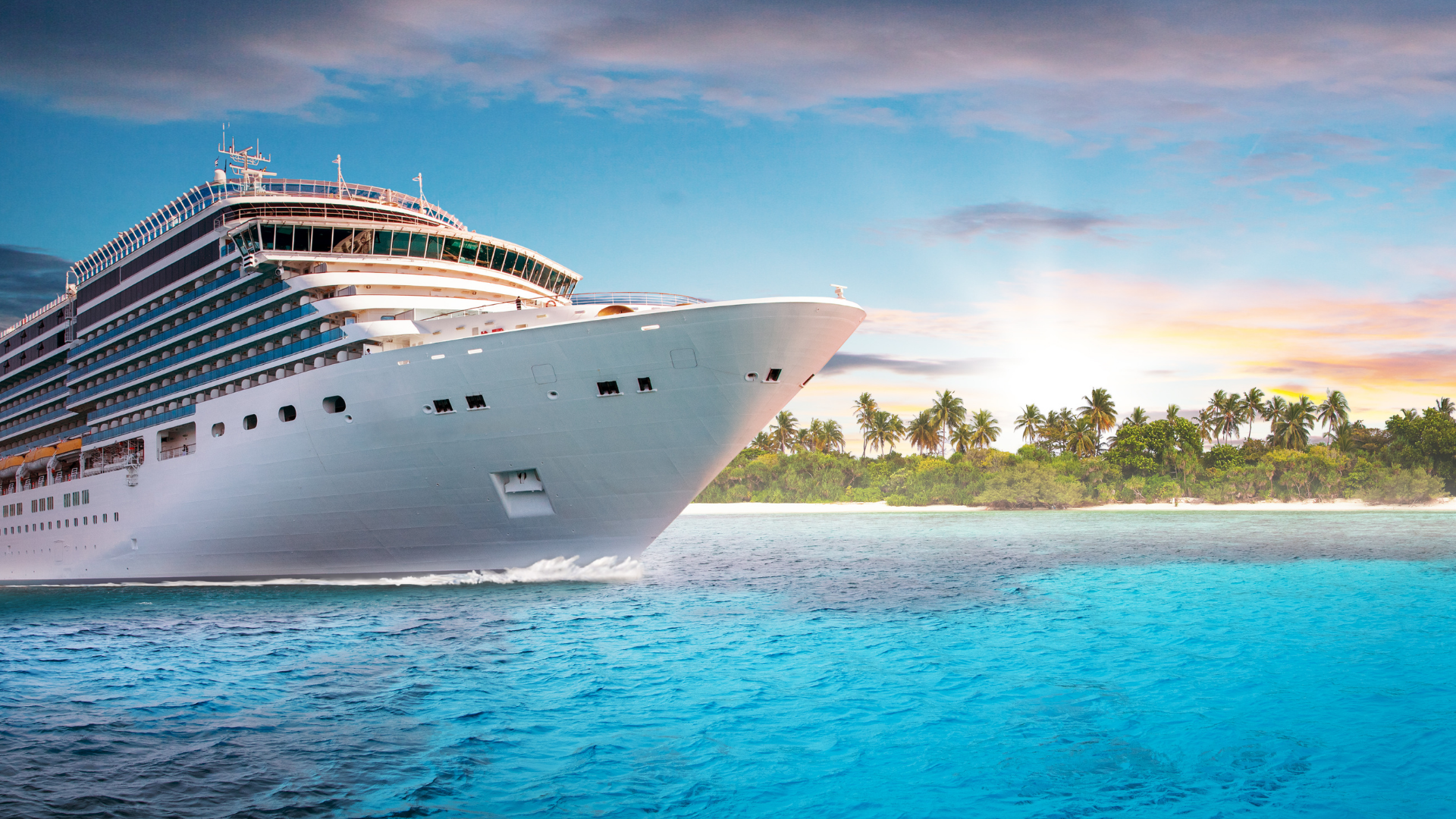 A large cruise ship sailing near a tropical island with palm trees at sunset.