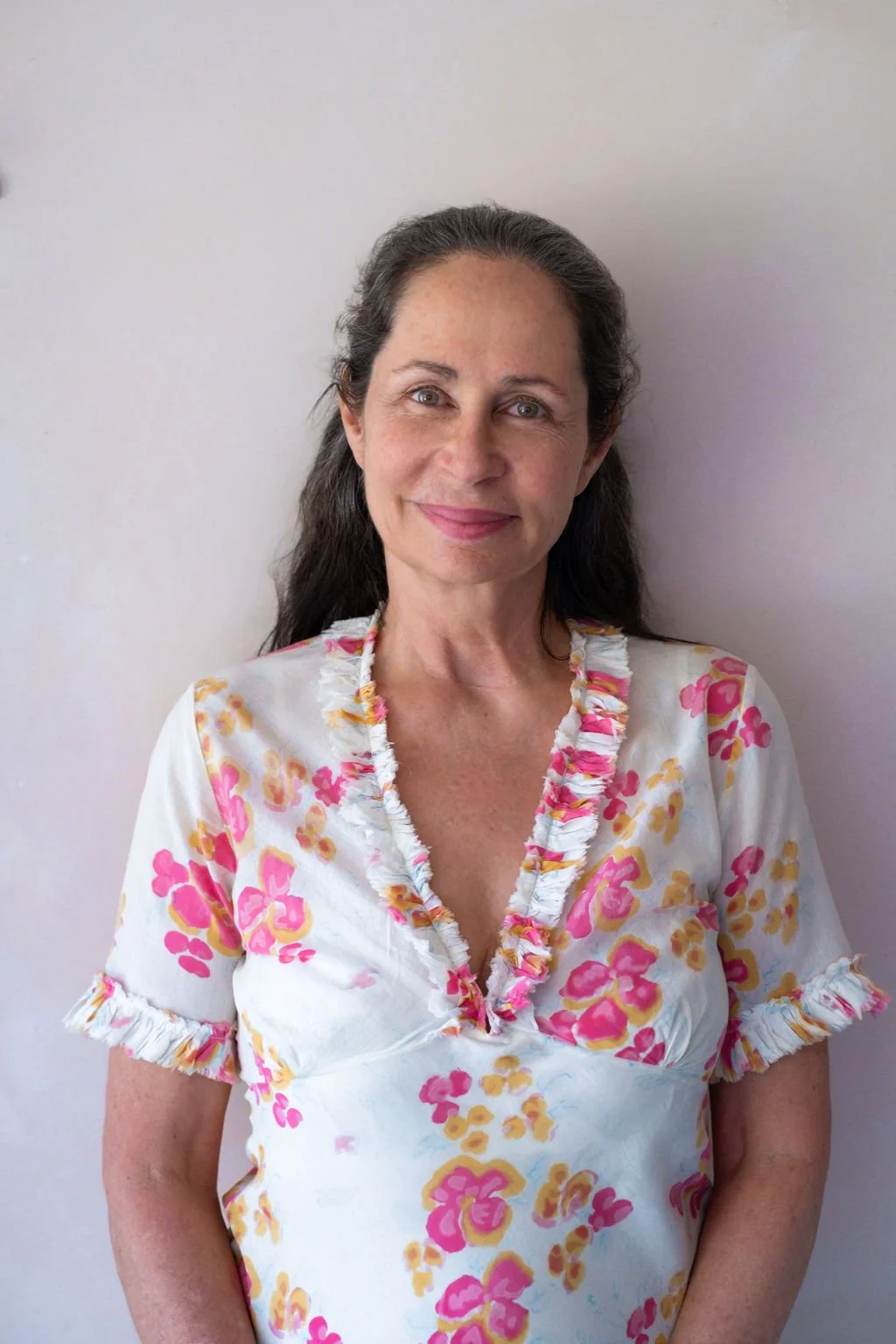 A portrait of a woman with long dark hair in a floral shirt, positioned inside a table cell.