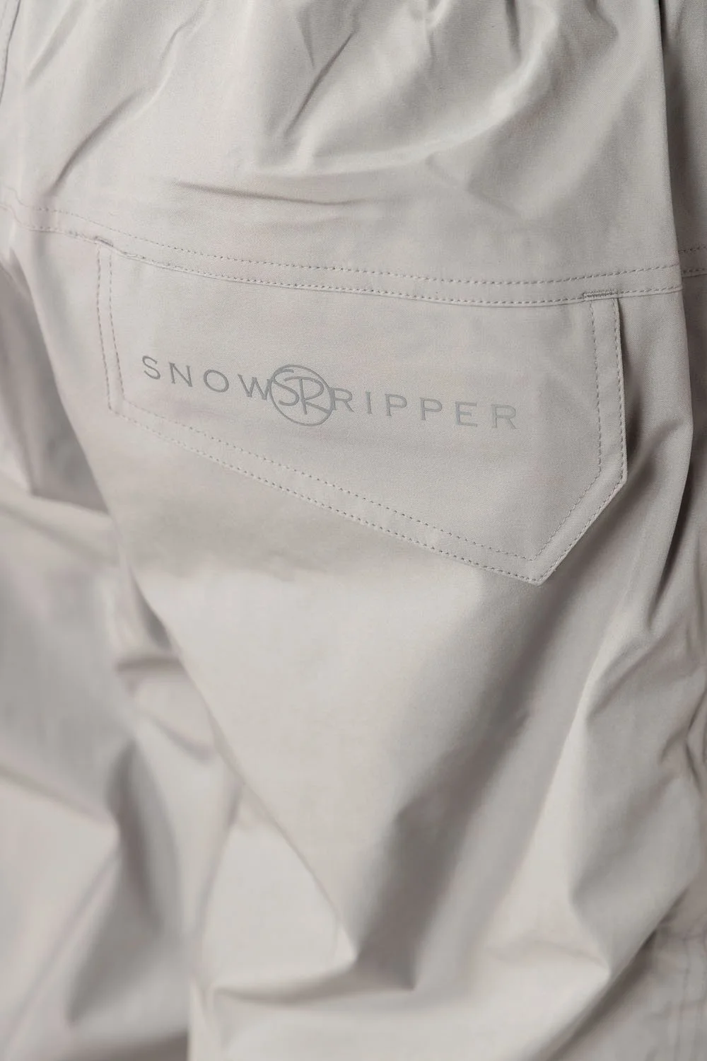 Close-up of Snowripper logo on back pocket of Cool Gray Drift Pants.