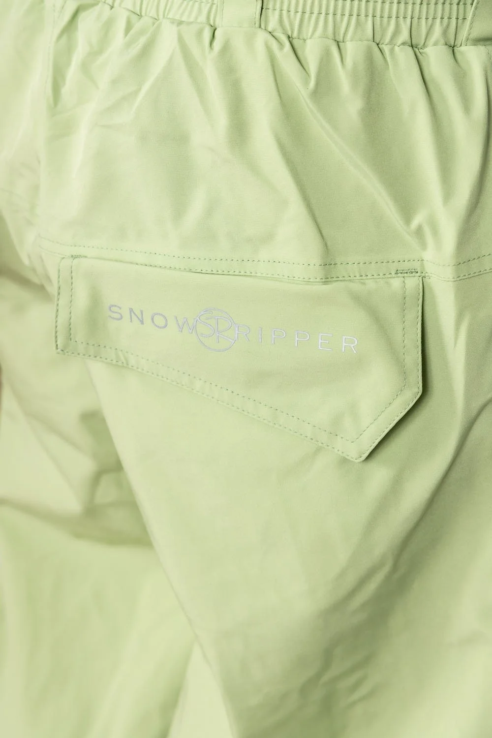 Close-up of Snowripper logo on back pocket of Mist Green Drift Pants.