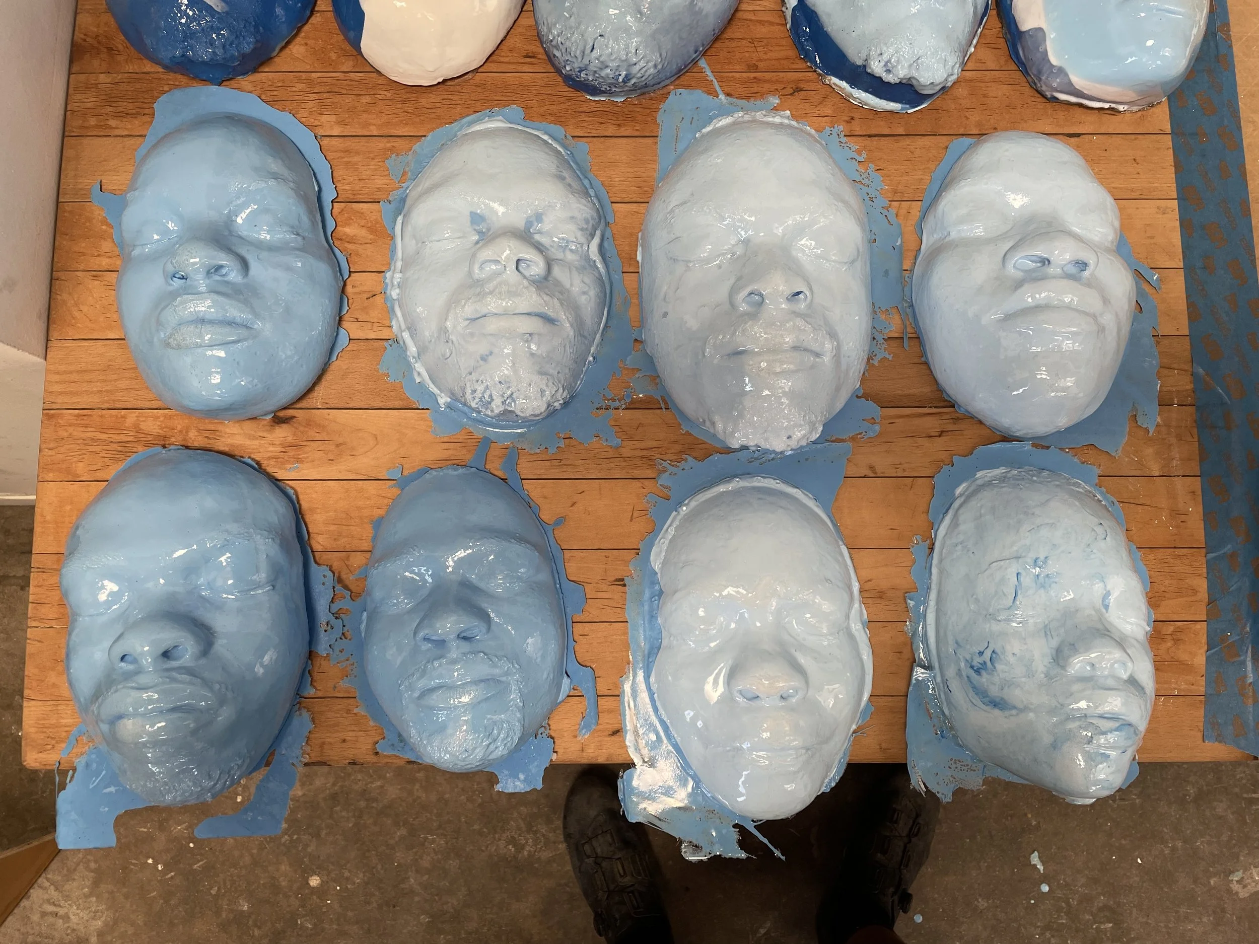 Blue plaster face molds on a wooden surface.
