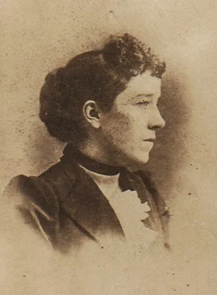 Sepia colored photograph of a woman. She is looking to her left. Ellen Goulding Canfield.