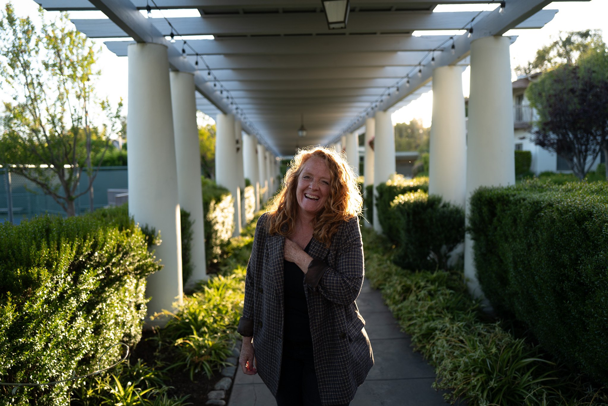 Malaurie Hotier laughing while walking through a garden colonnade