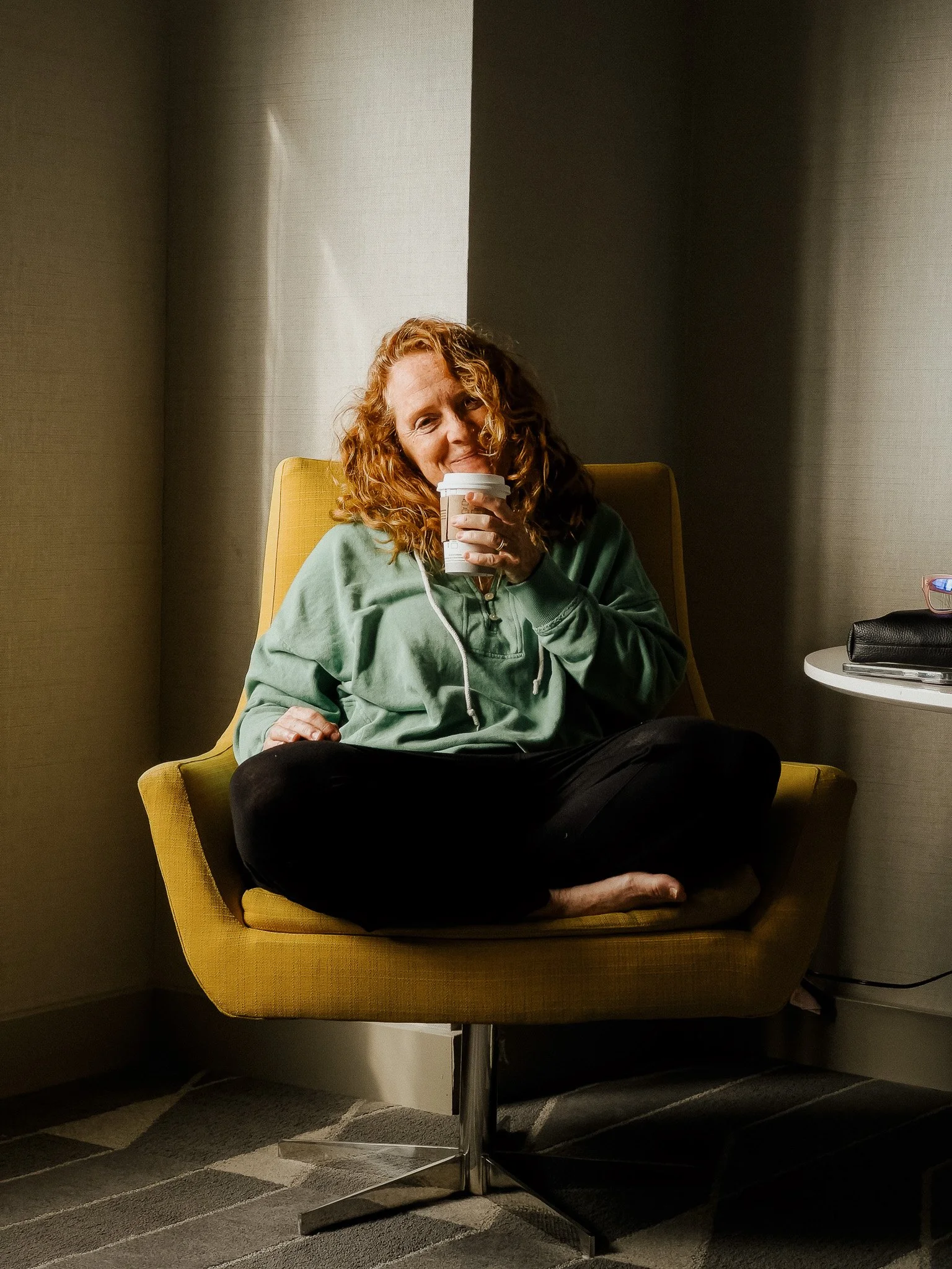 Malaurie Hotier sitting with a coffee in a yellow armchair