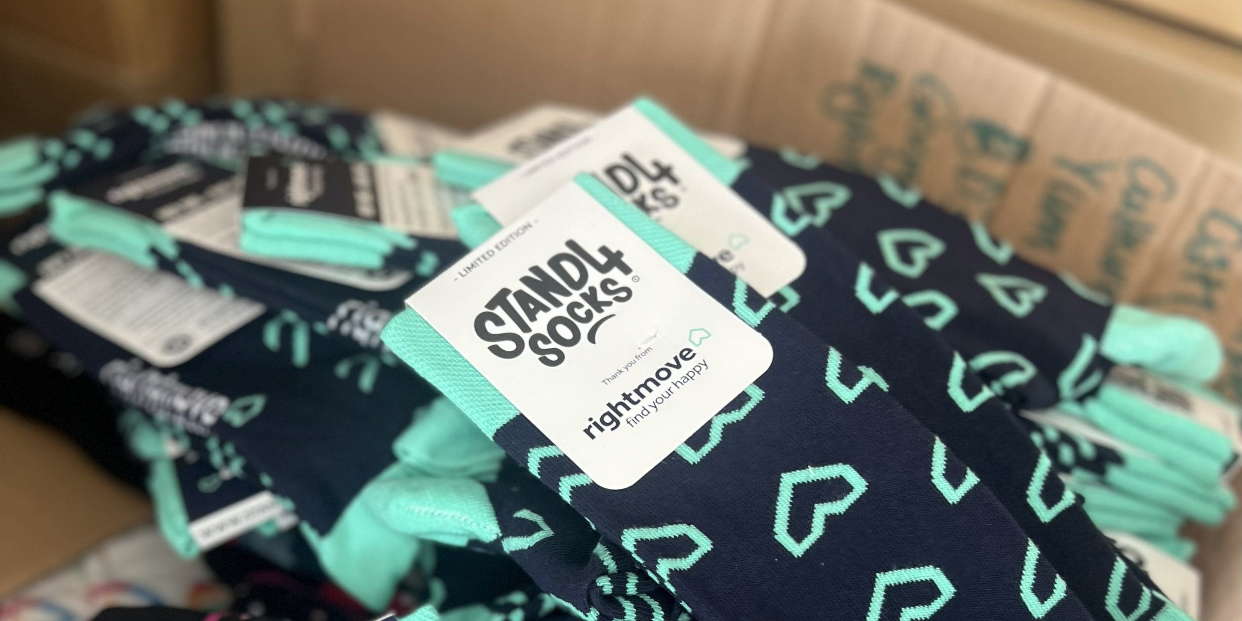 Custom Stand4 socks and branded packaging displayed as personalised client gift ideas for renewals and account milestones