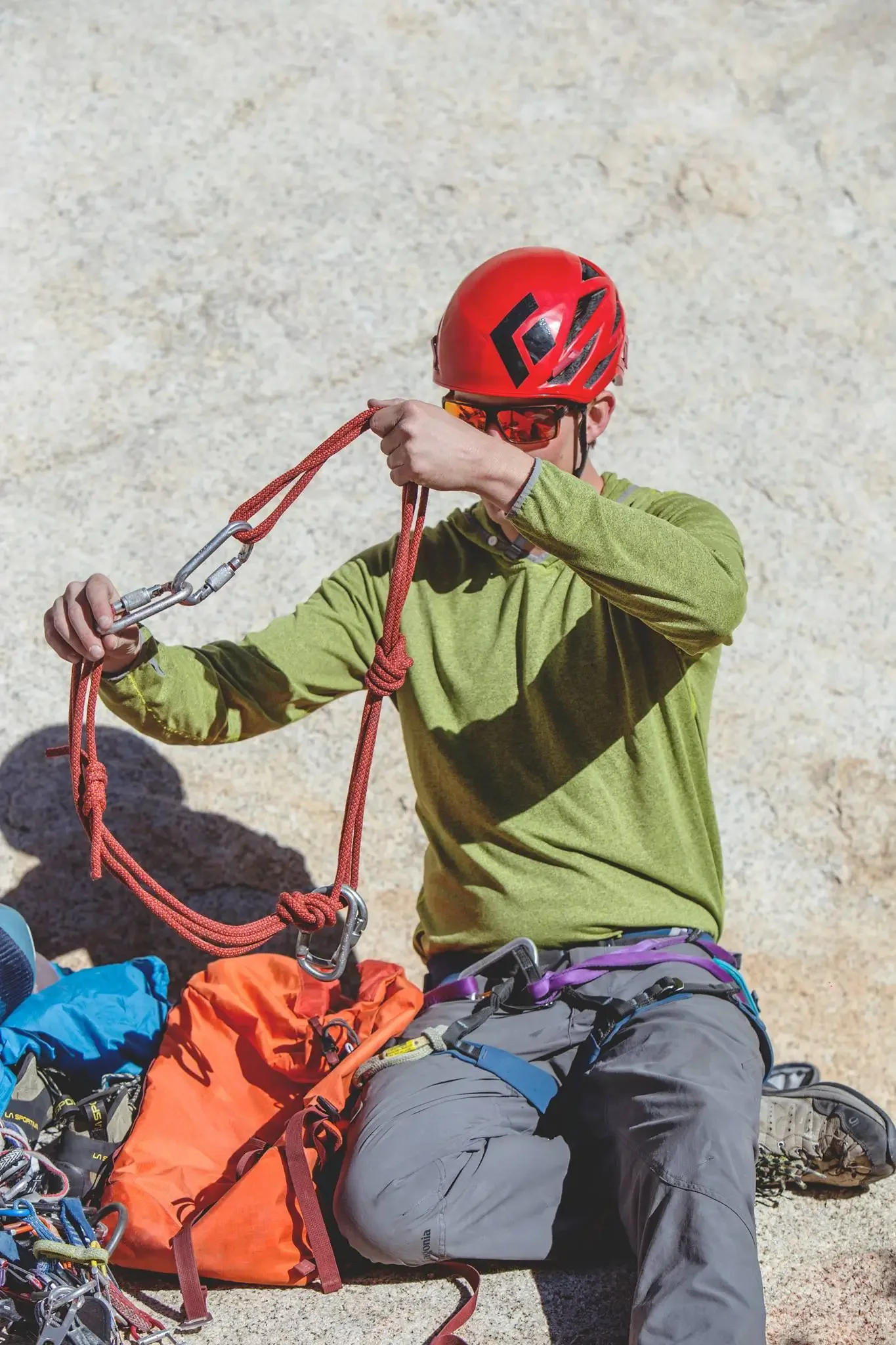 A person rock climbing on a steep granite wall, using climbing gear and a safety rope.