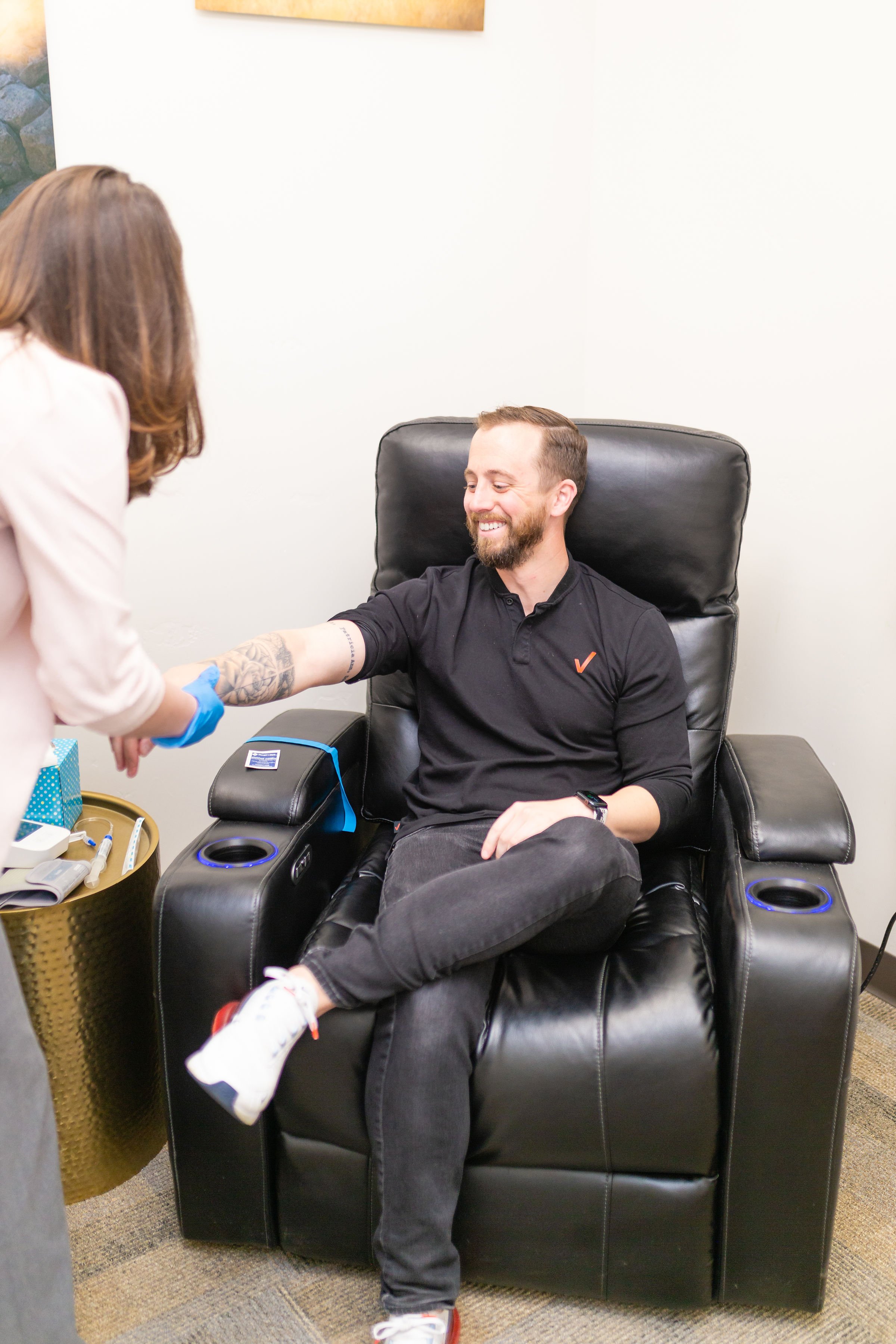 Man receiving medical treatment in a recliner with a healthcare professional taking his arm.