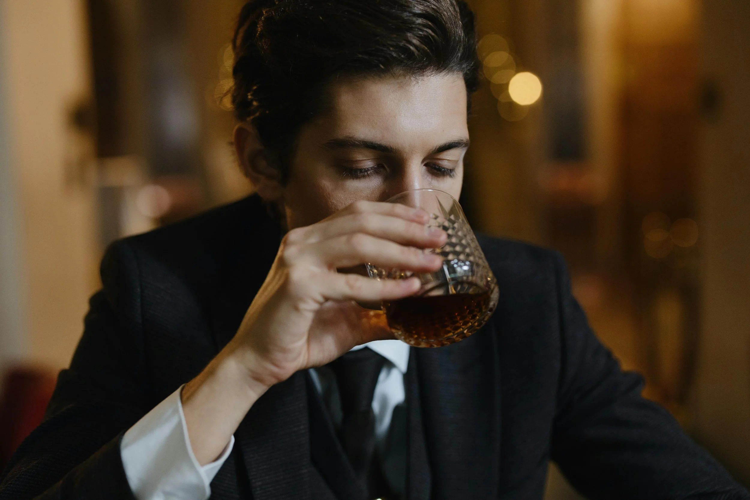 A tired-looking man slumped over a table holding a bottle