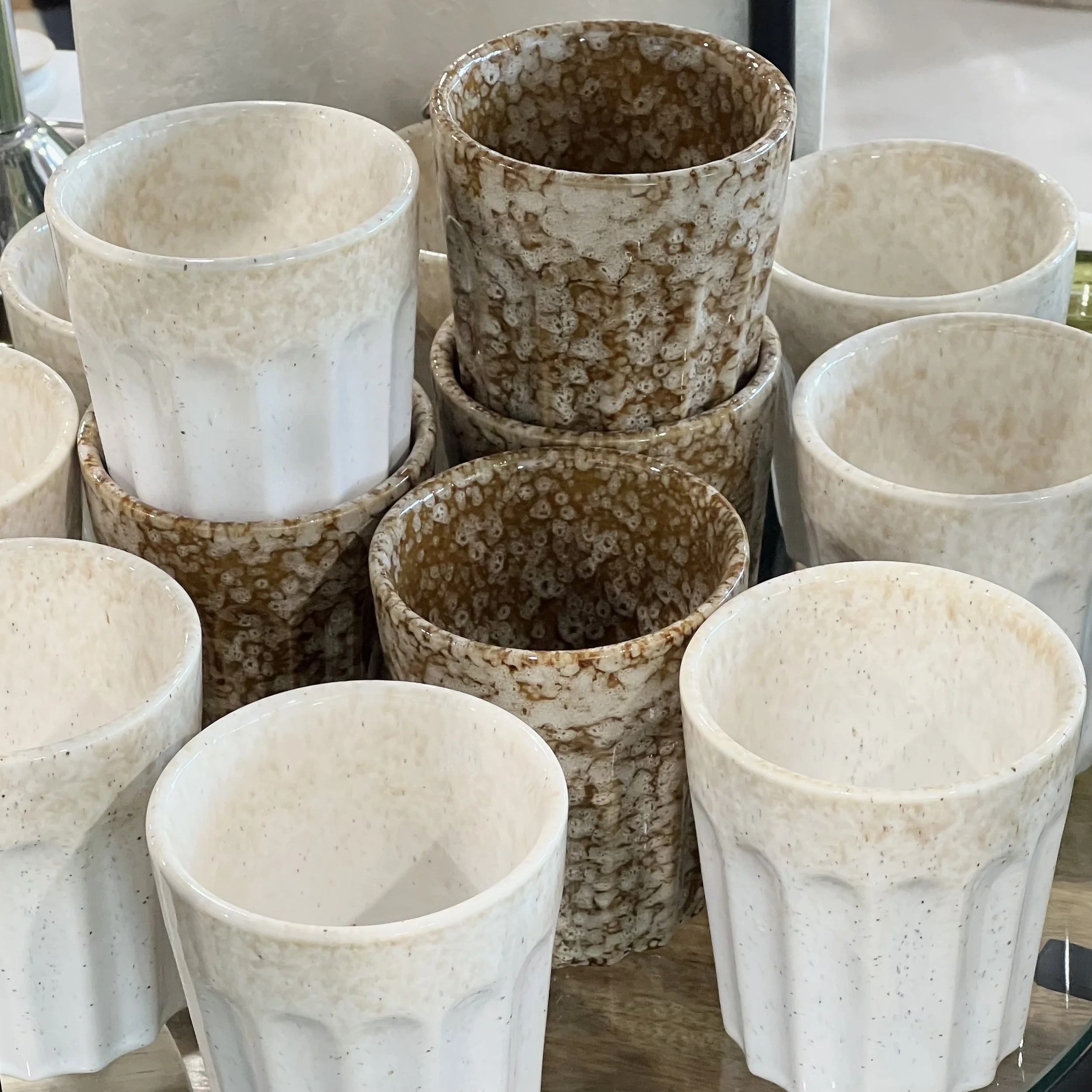 Stacked Studio ceramic cups in white and brown, with textured designs.