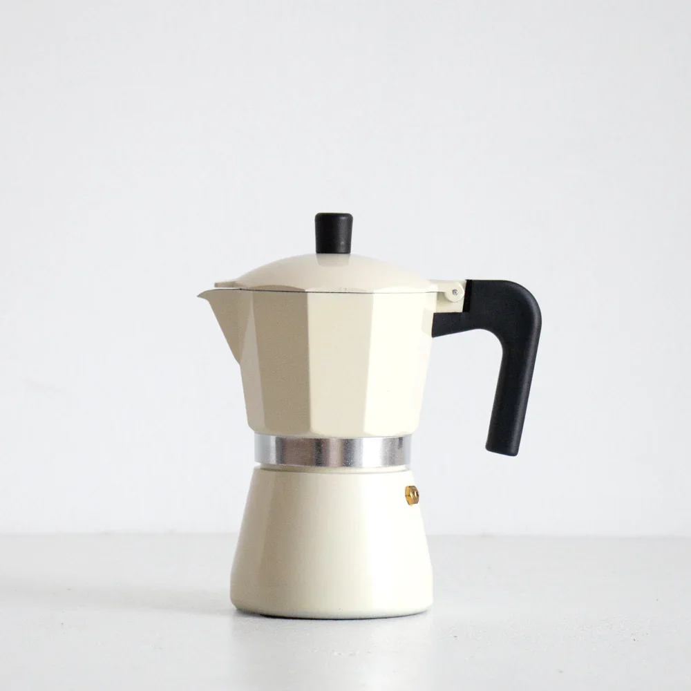 A vintage white moka pot coffee maker with a black handle and lid on a white surface against a white background.
