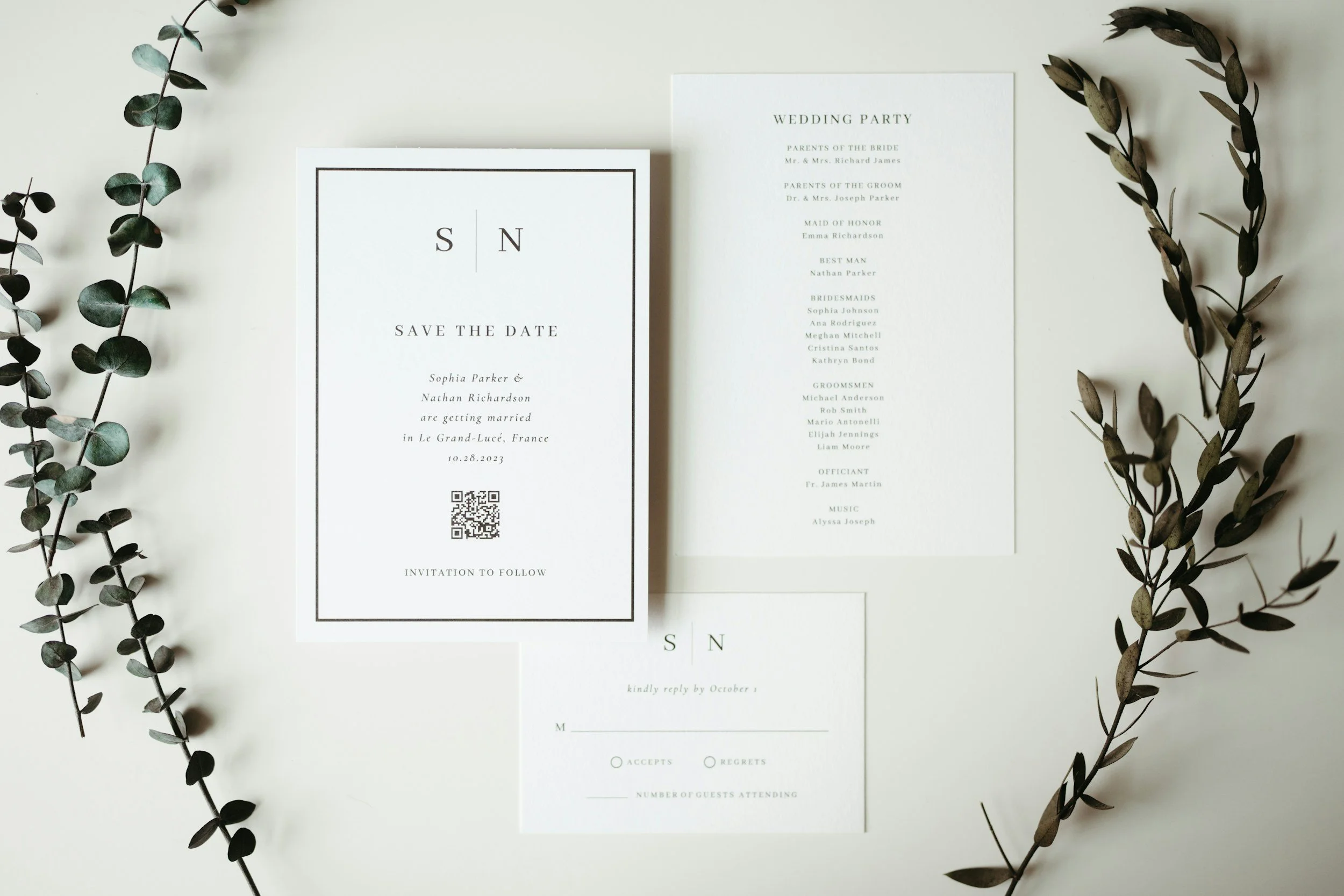 Wedding invitation suite including a save-the-date card, wedding program, RSVP card, and greenery accents